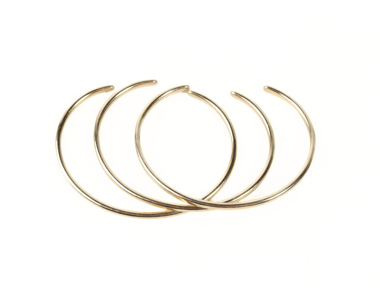 A group of gold-colored bracelets arranged in a circular pattern against a white background.