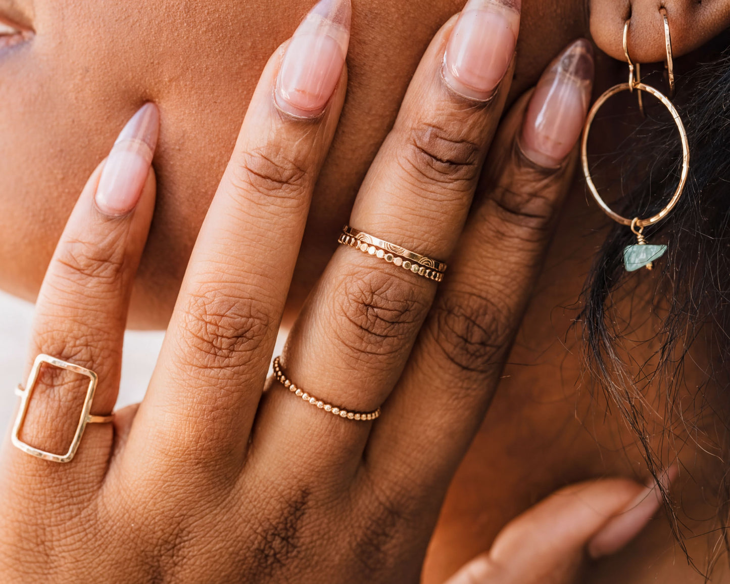 A close-up of a person's hand adorned with multiple rings and earrings, showcasing their unique style and fashion sense.