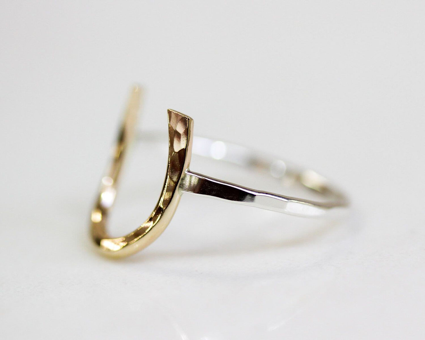 A ring with a unique, curved design made of two different metals, likely gold and silver.