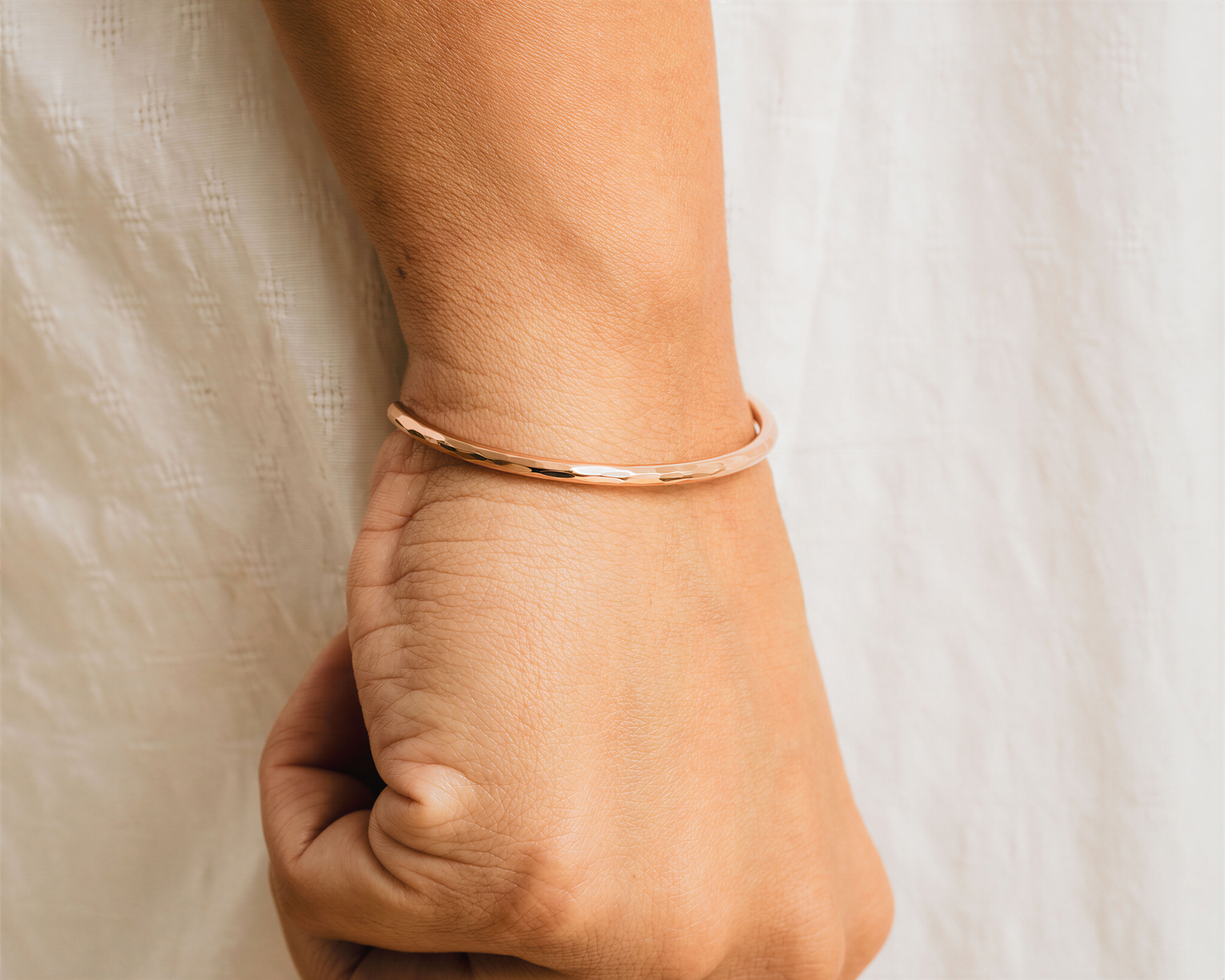 A close-up view of a person's wrist wearing a gold-colored bracelet.