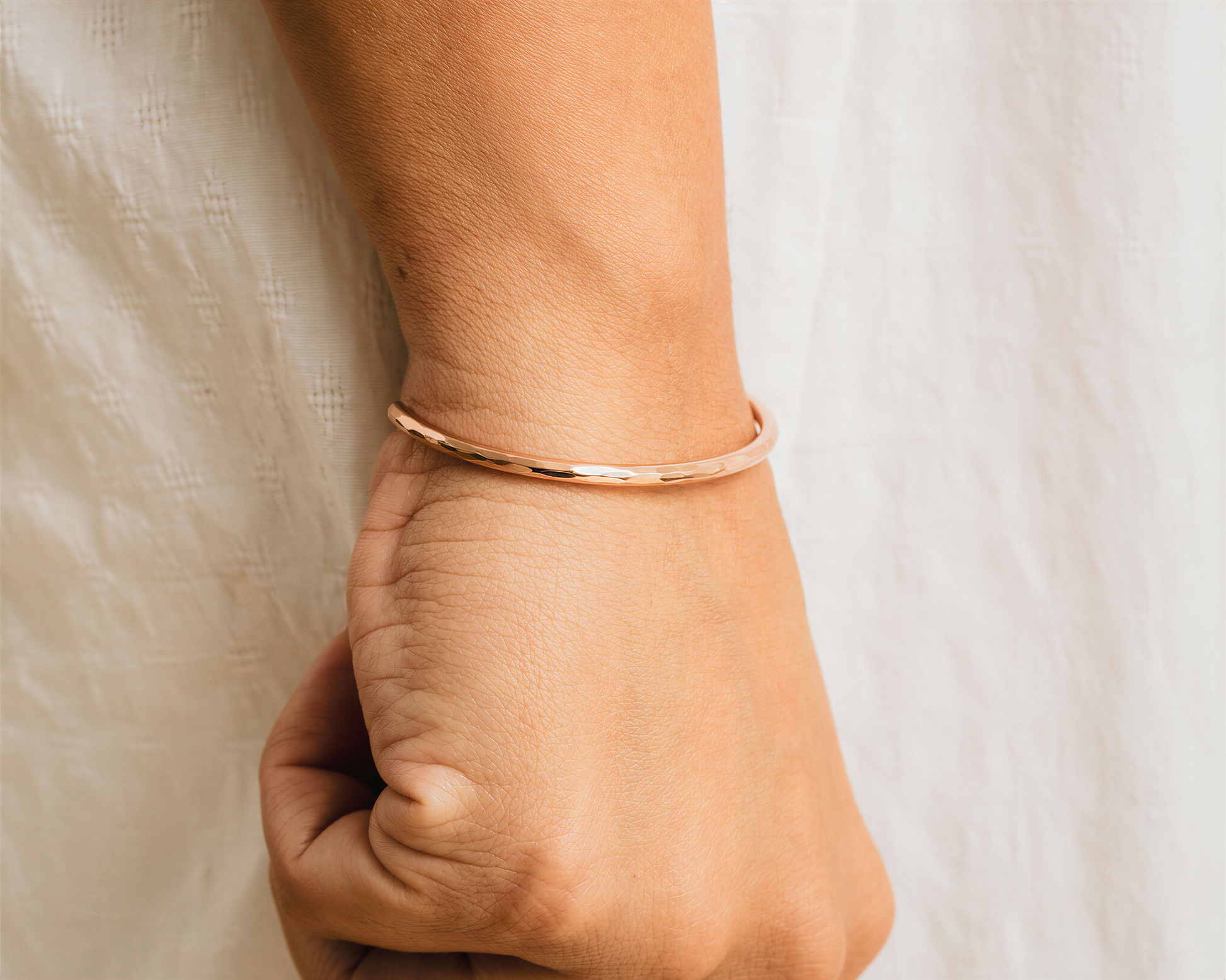 A close-up view of a person's wrist wearing a gold-colored bracelet.