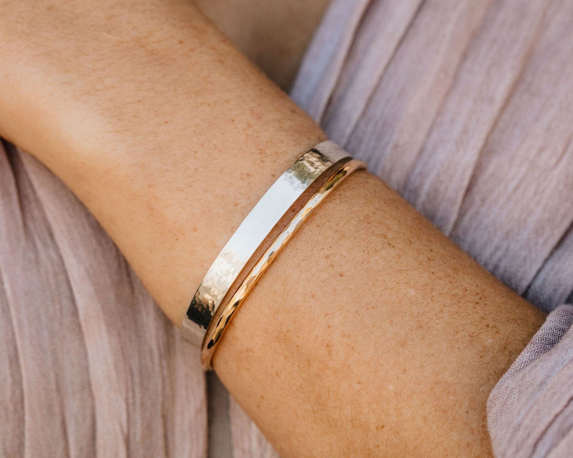 A close-up view of a person's arm wearing a gold and silver bracelet.