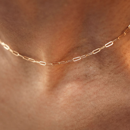 A close-up view of a delicate gold chain necklace worn around a person's neck.