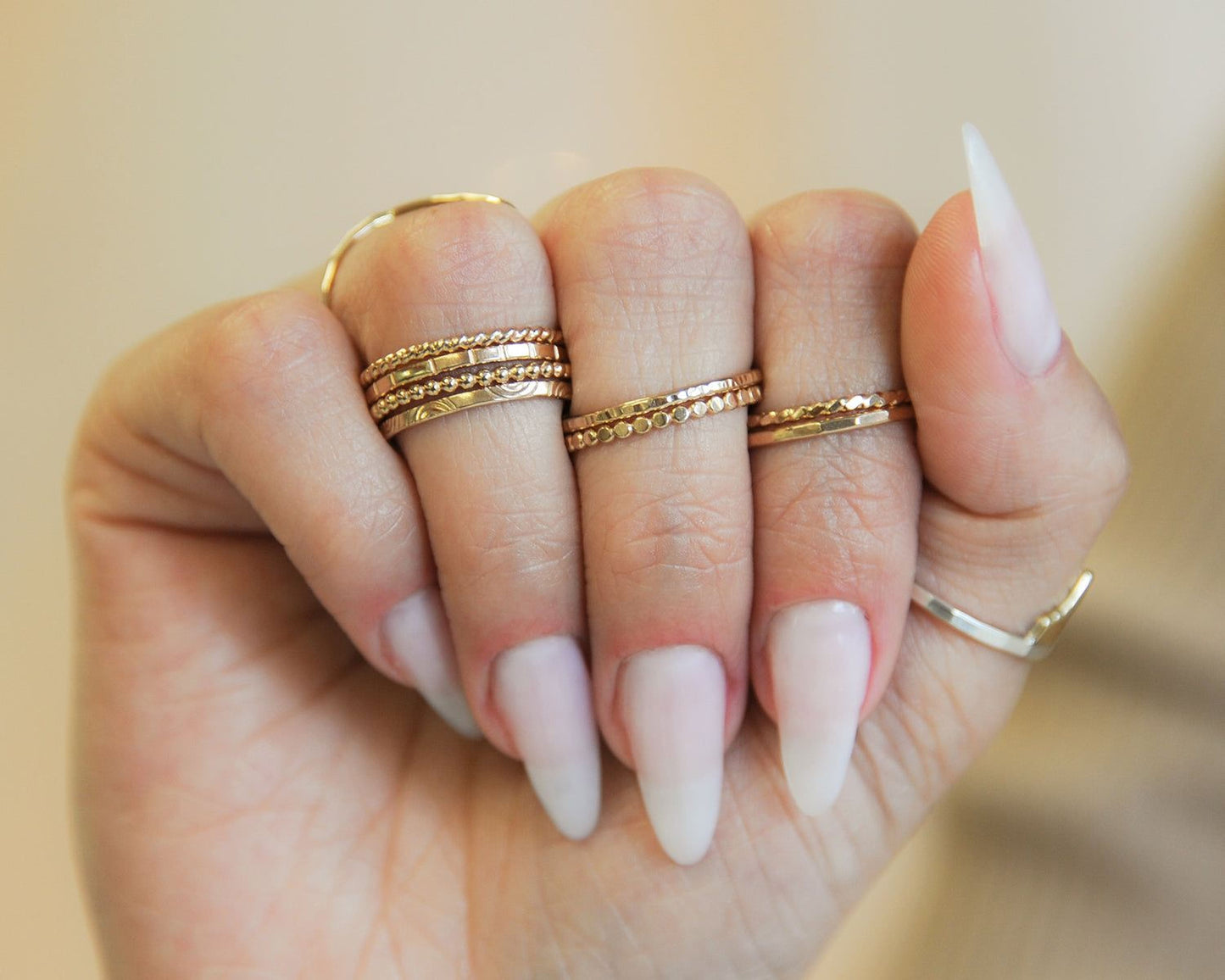 A close-up of a person's hand wearing multiple rings on their fingers.