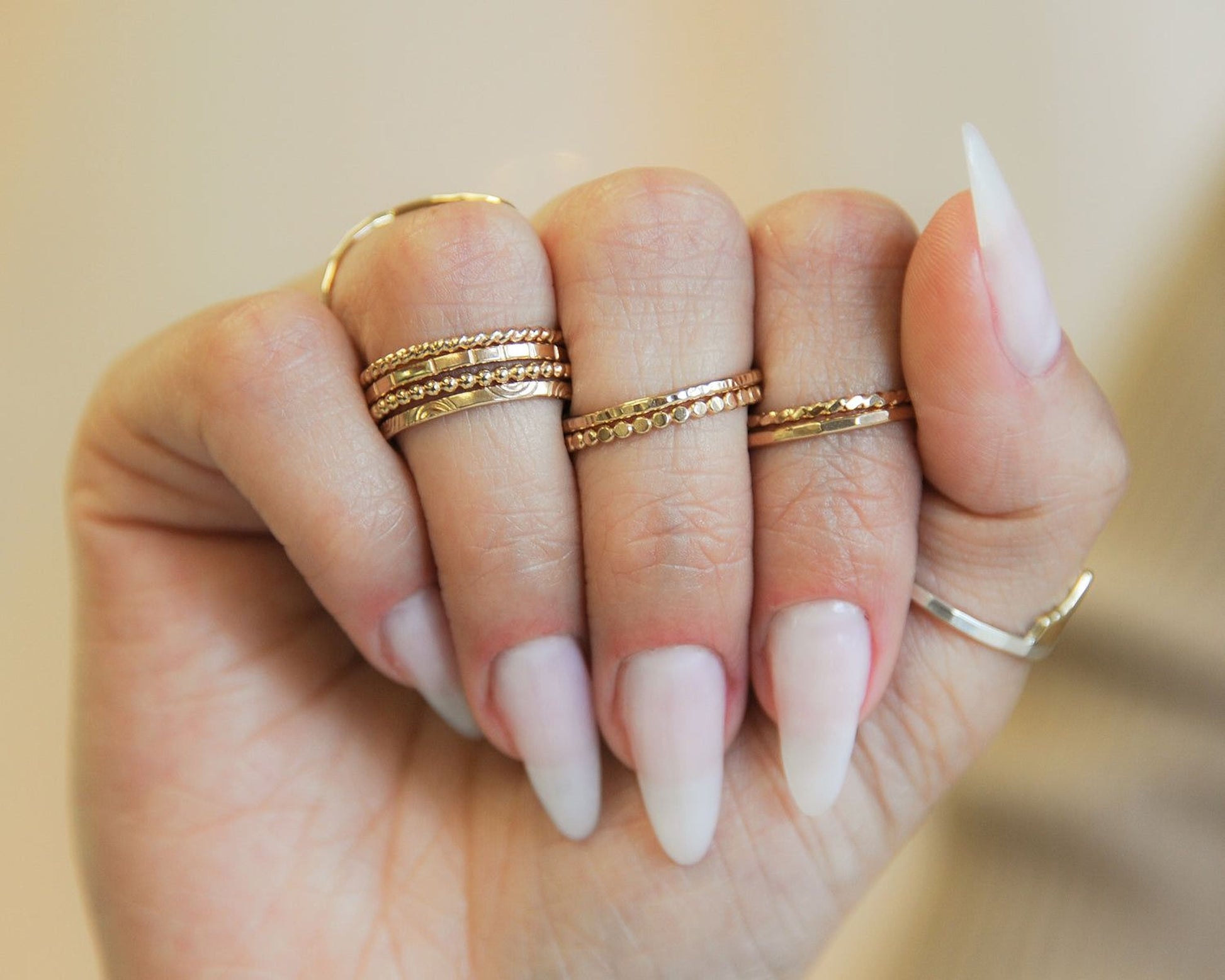 A close-up of a person's hand wearing multiple rings on their fingers.