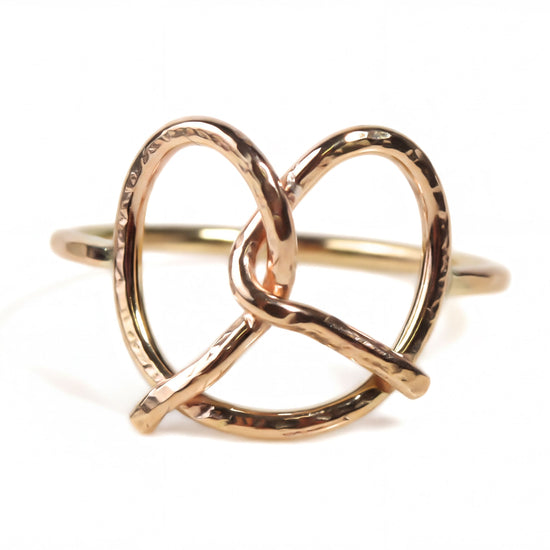 A gold-colored ring with a twisted, braided design resembling a pretzel.