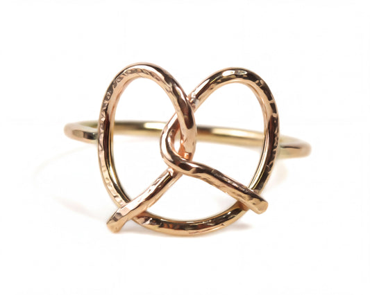 A gold-colored ring with a twisted, braided design resembling a pretzel.