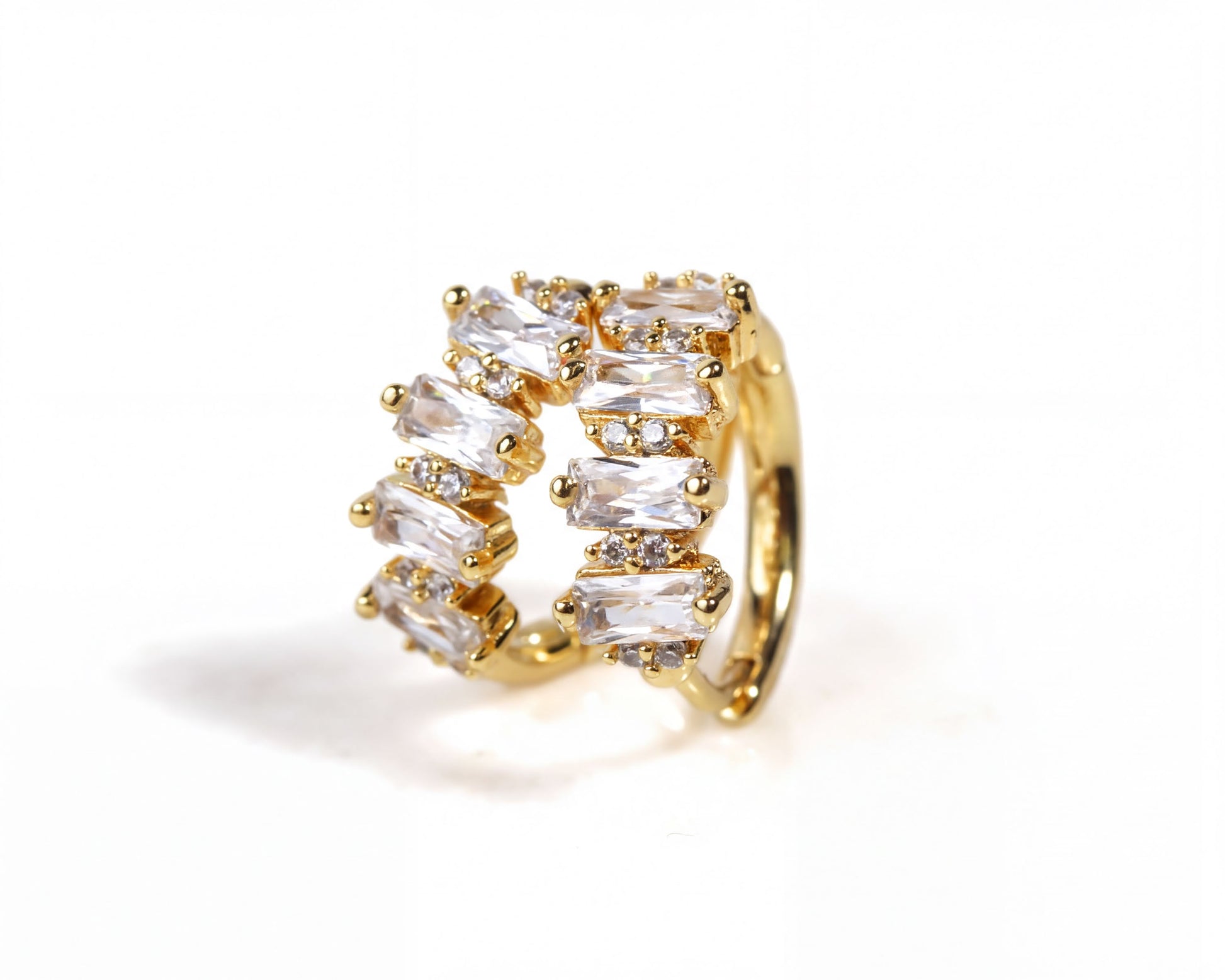 A gold earring with a row of clear gemstones, including diamonds, set in a decorative manner.