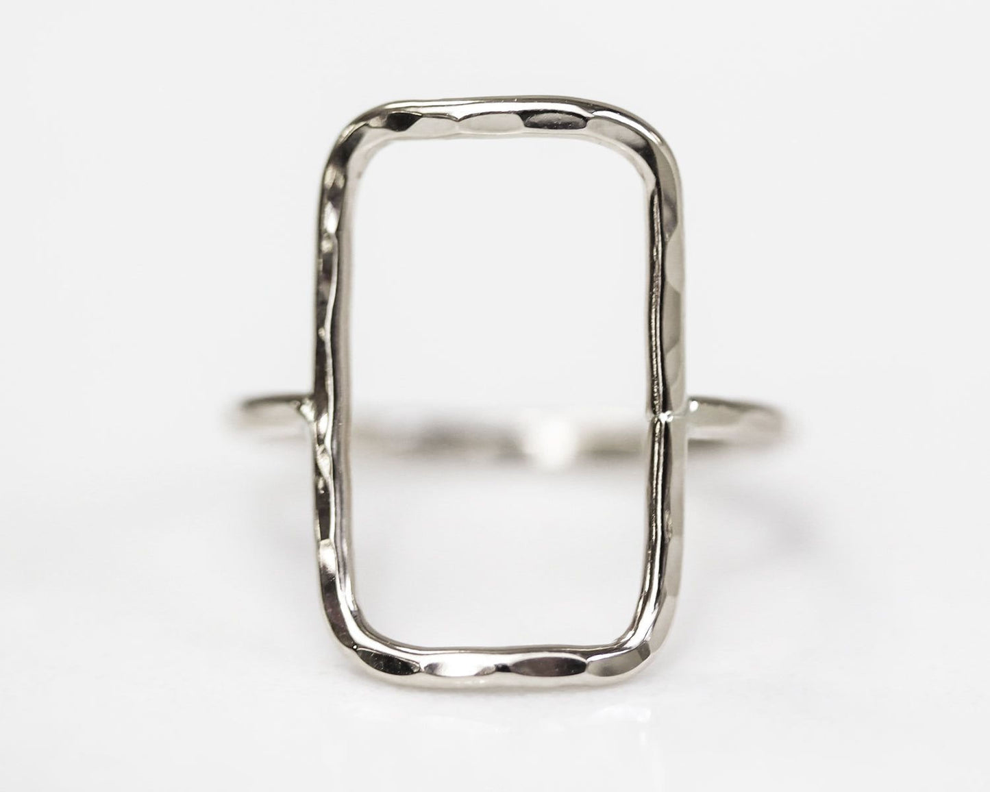A silver ring with a unique, irregularly shaped frame.