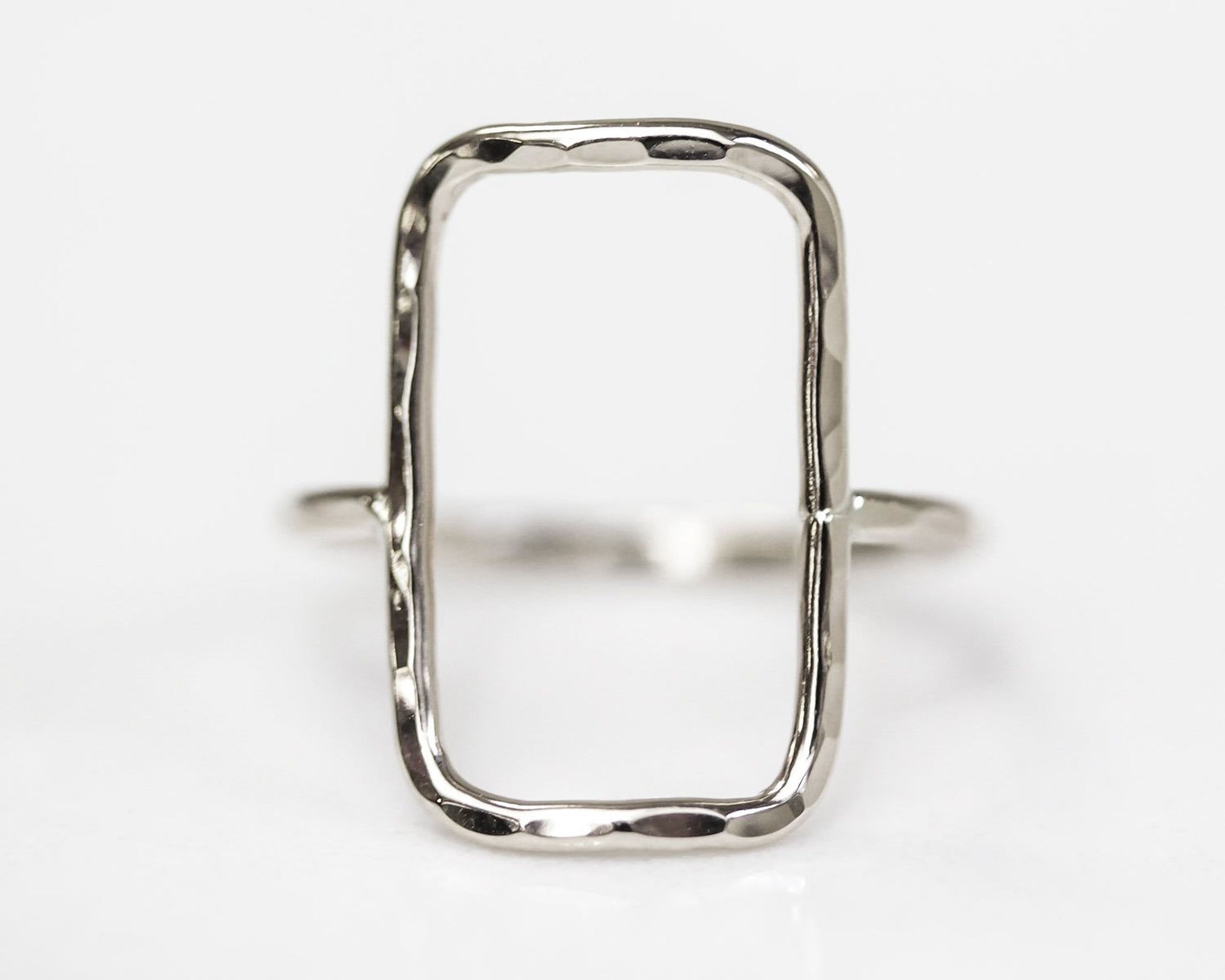 A silver ring with a unique, irregularly shaped frame.