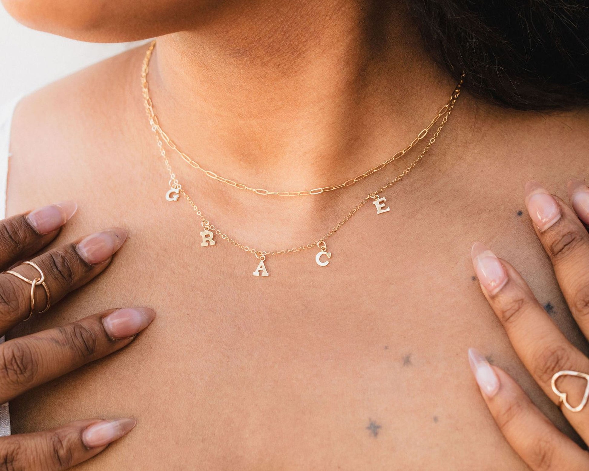 A close-up of a person's chest wearing a necklace with the name "Grace" engraved on it.