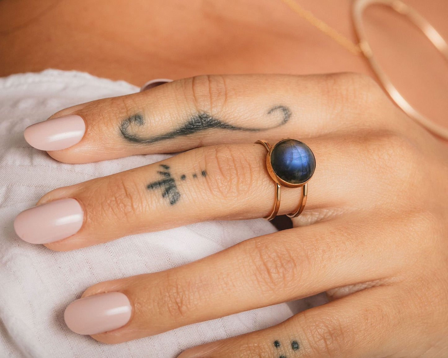 A close-up of a person's hand with a ring on one finger and a tattoo on the other.