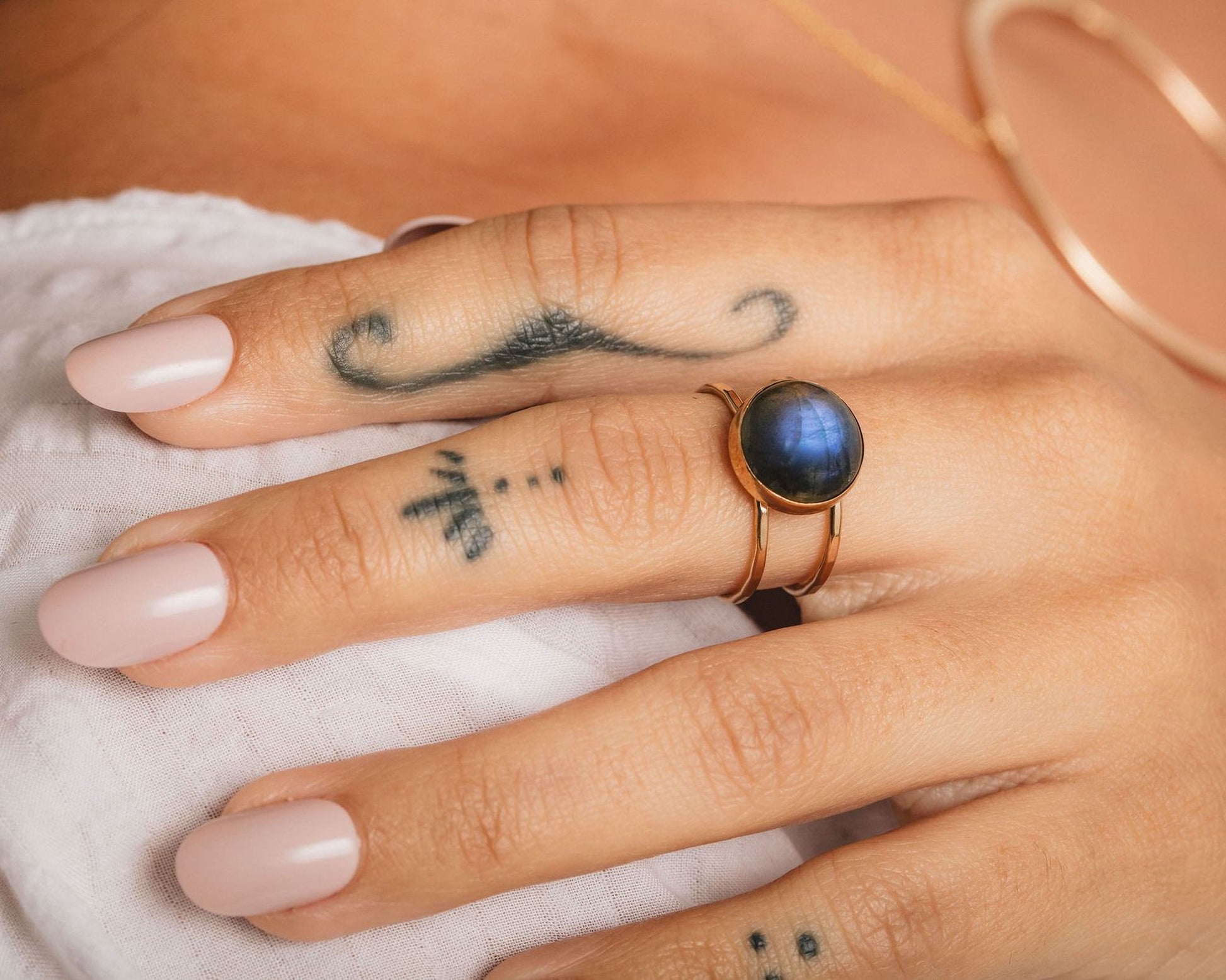 A close-up of a person's hand with a ring on one finger and a tattoo on the other.