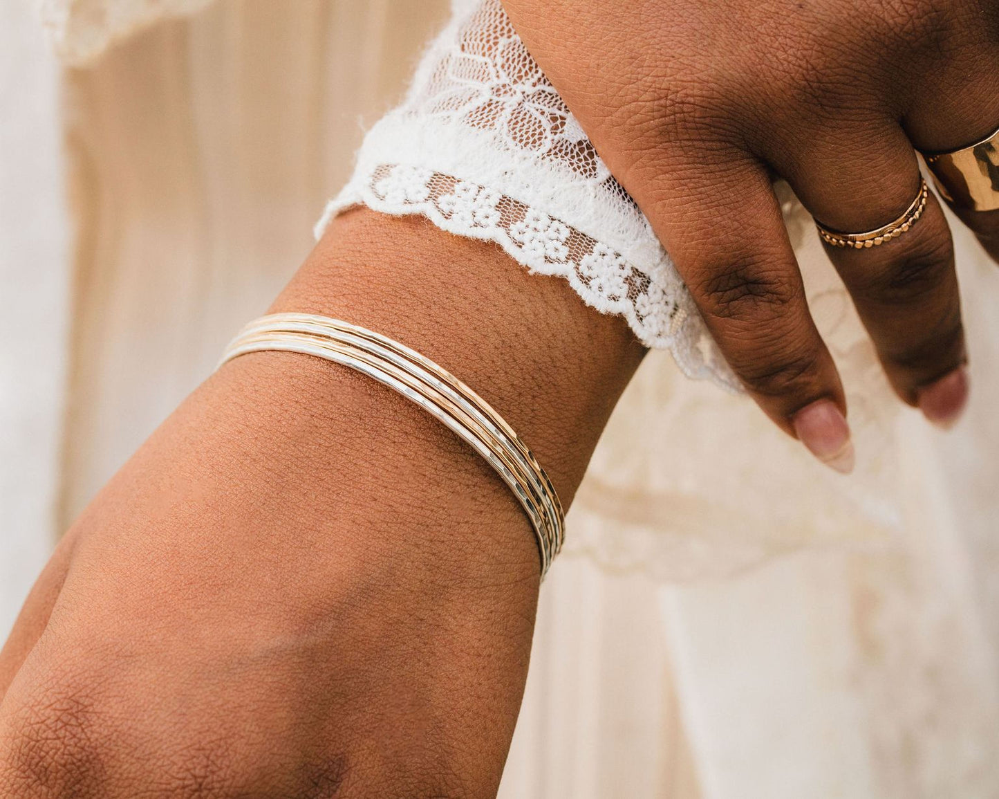 A close-up view of a person's wrist wearing multiple bracelets and rings.
