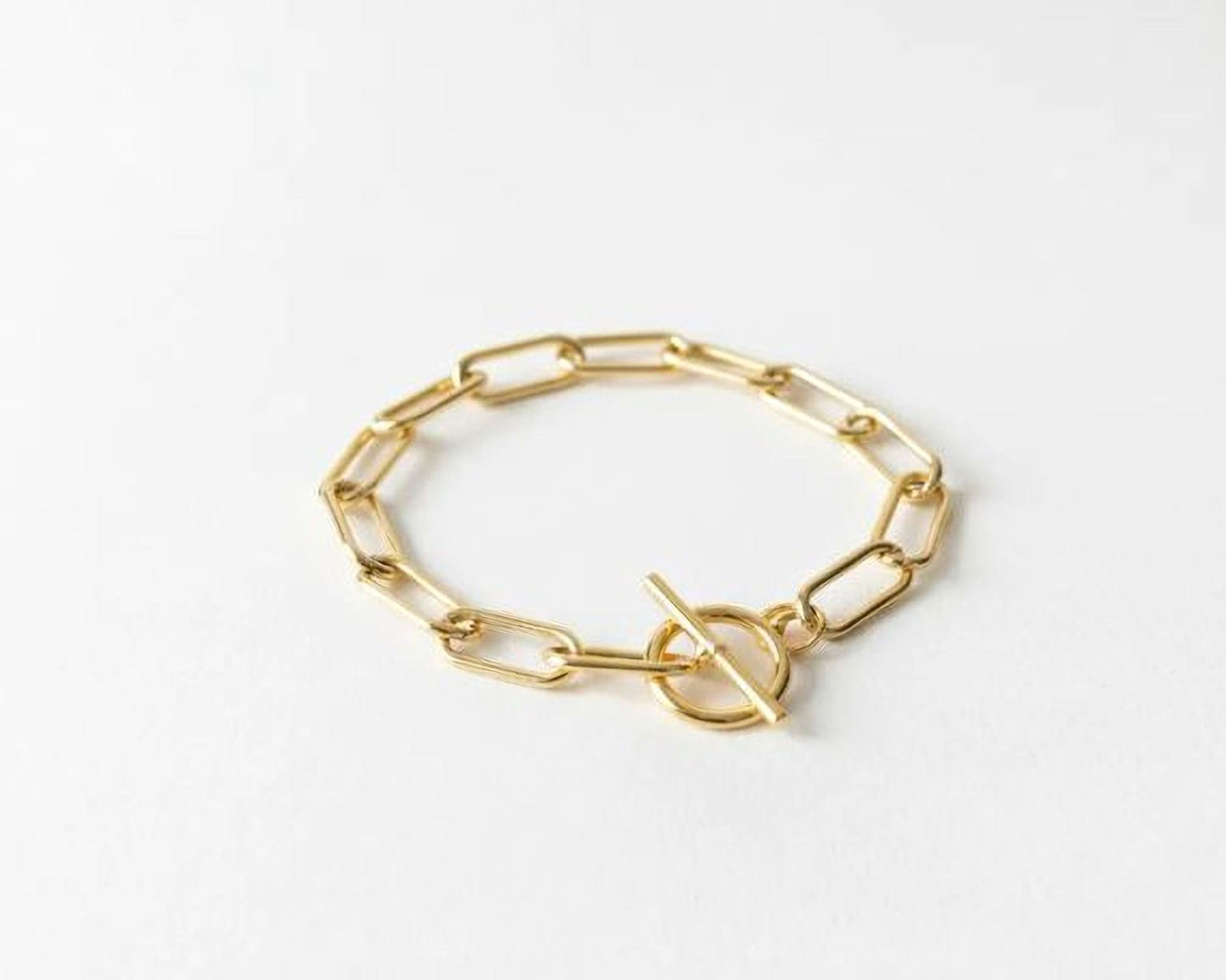 A gold-colored bracelet with a simple, minimalist design consisting of a series of interlocking links.