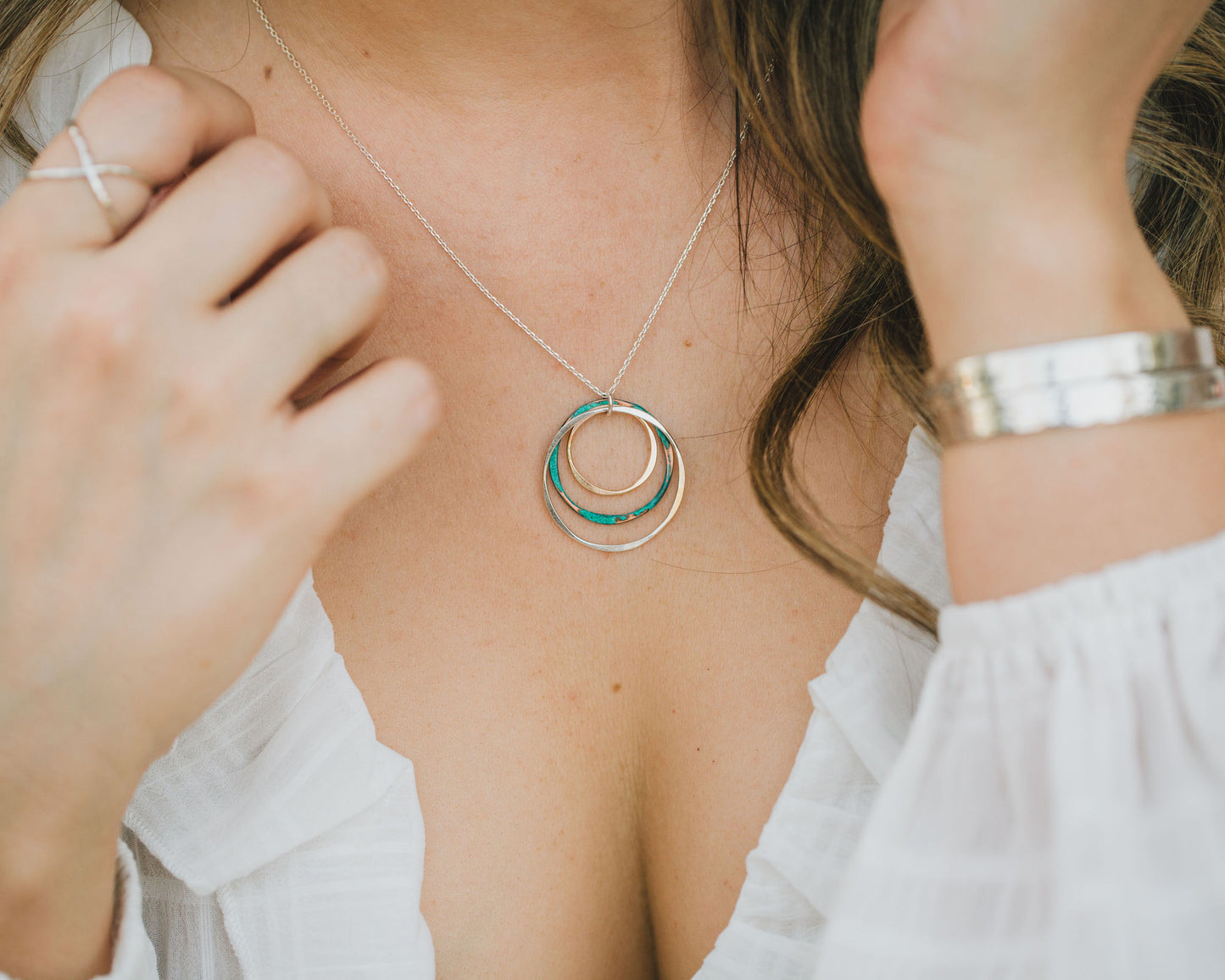 Three precious organically shaped hoops make up this design. Each is meticulously handcrafted. The largest 925 Sterling Silver hoop measures 1 inch. Mint patina over Copper and 14 Karat Gold Filled hoops gleam within. Shown here close up on our model