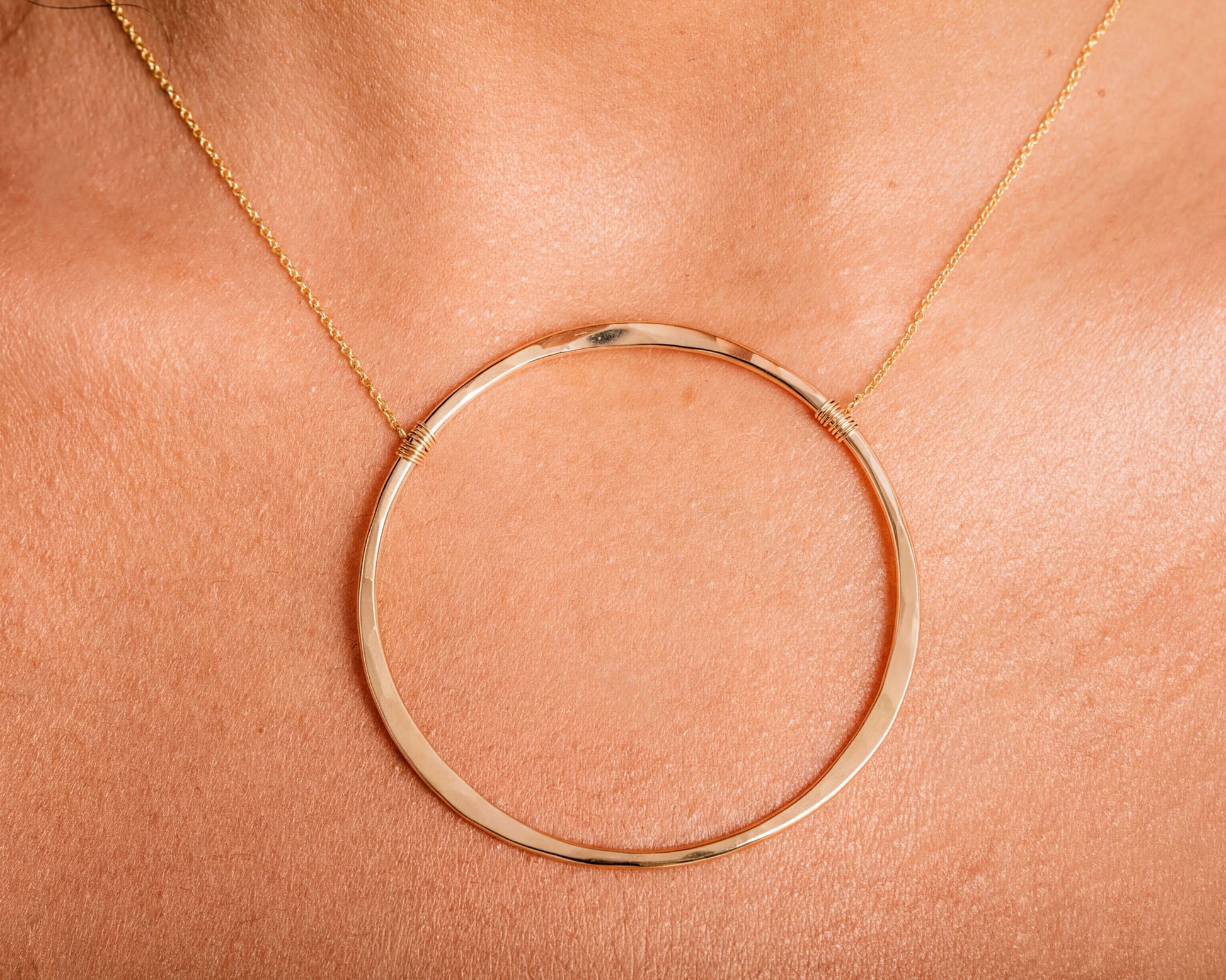 A close-up view of a gold-colored necklace with a large circular pendant.