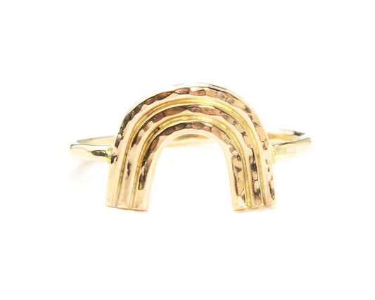 A gold ring with a unique, handcrafted design resembling a rainbow.