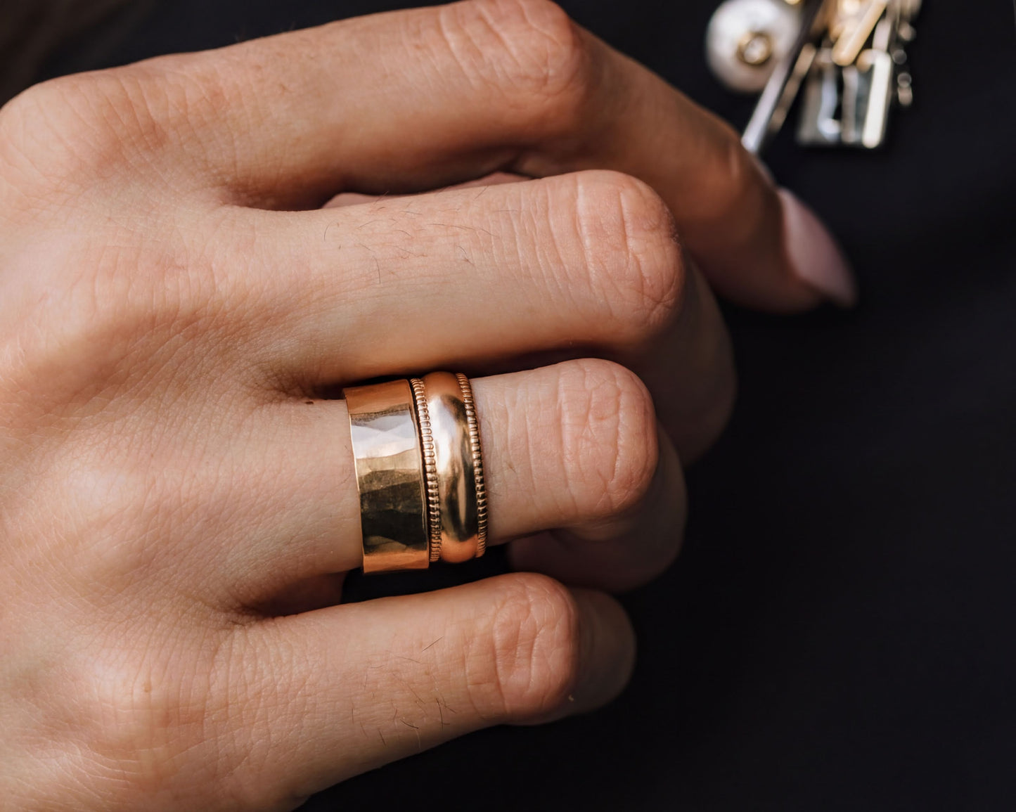 A close-up view of a person's hand wearing a gold ring on the ring finger.