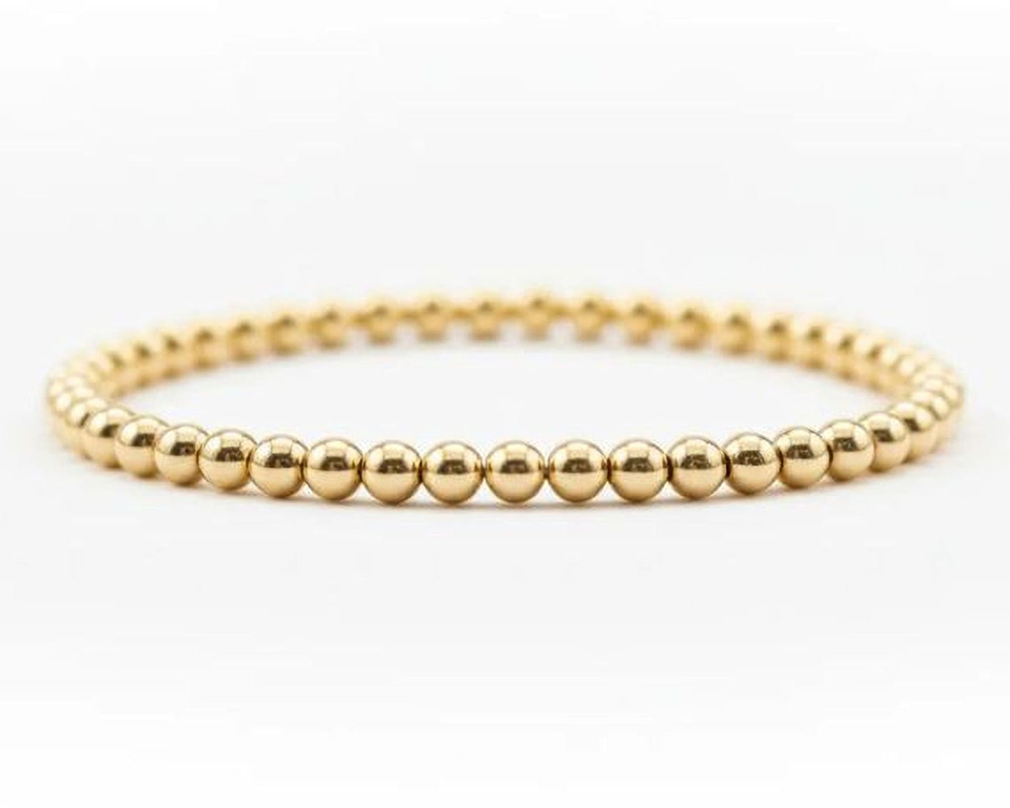 A gold-colored bracelet composed of numerous small, shiny gold beads arranged in a circular pattern.