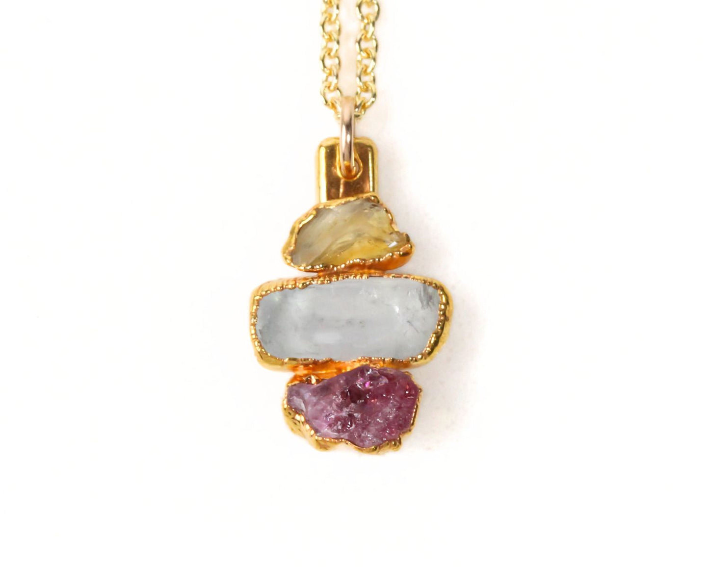 A necklace with a pendant featuring three different colored gemstones: a pale blue stone, a light yellow stone, and a deep purple stone.