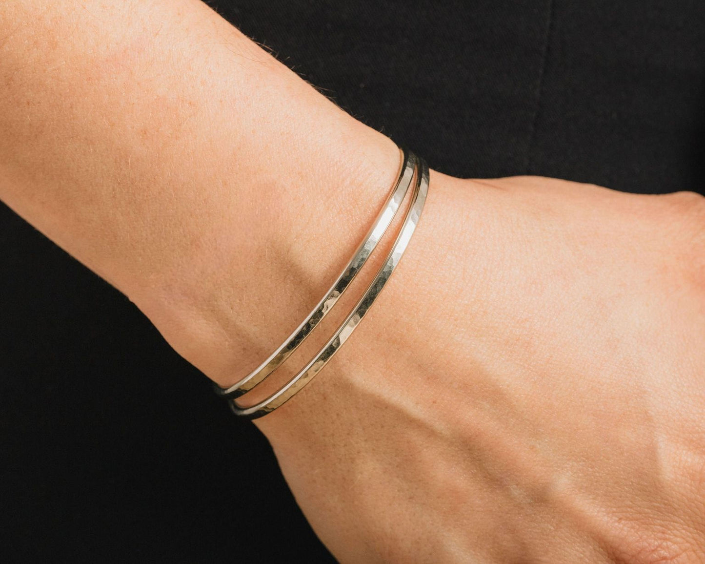 A close-up view of a person's wrist wearing a silver bracelet.