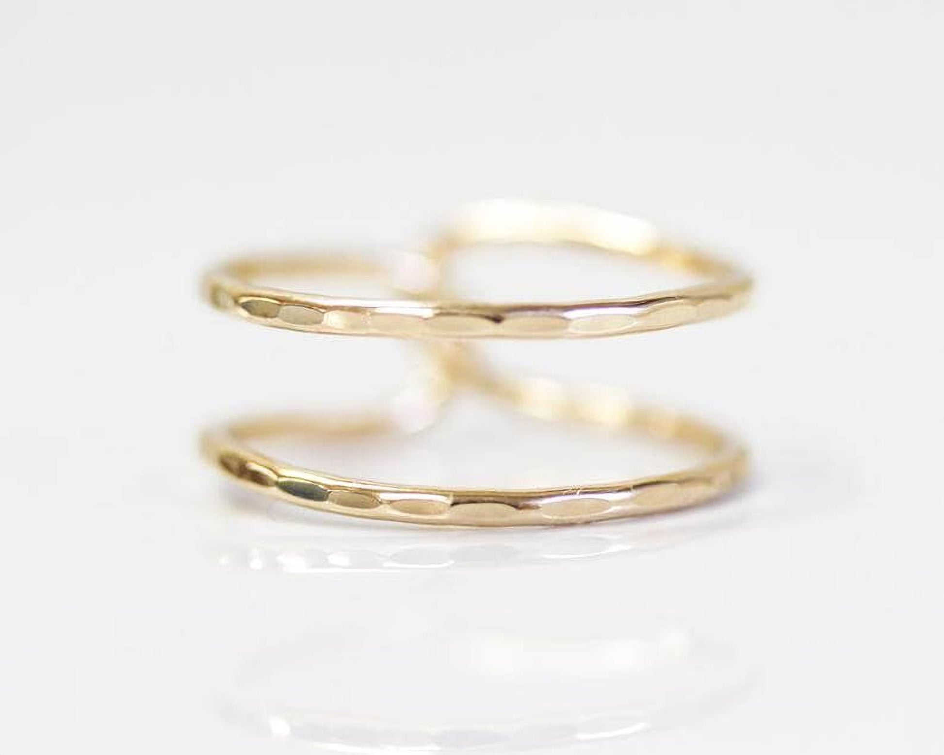 A close-up image of a gold ring with a textured surface, reflecting on a white background.