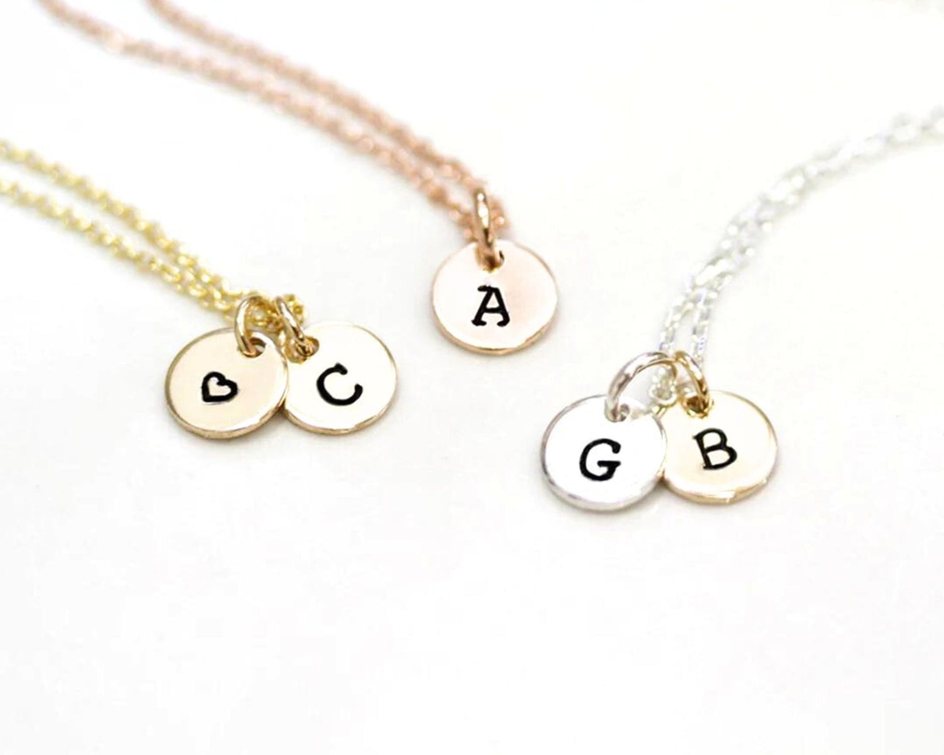 Three necklaces with small charms attached, each with a letter charm and a heart charm.