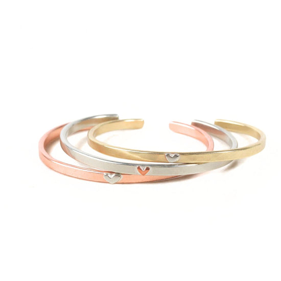 A group of three bracelets with heart-shaped charms on them, arranged in a circular pattern.