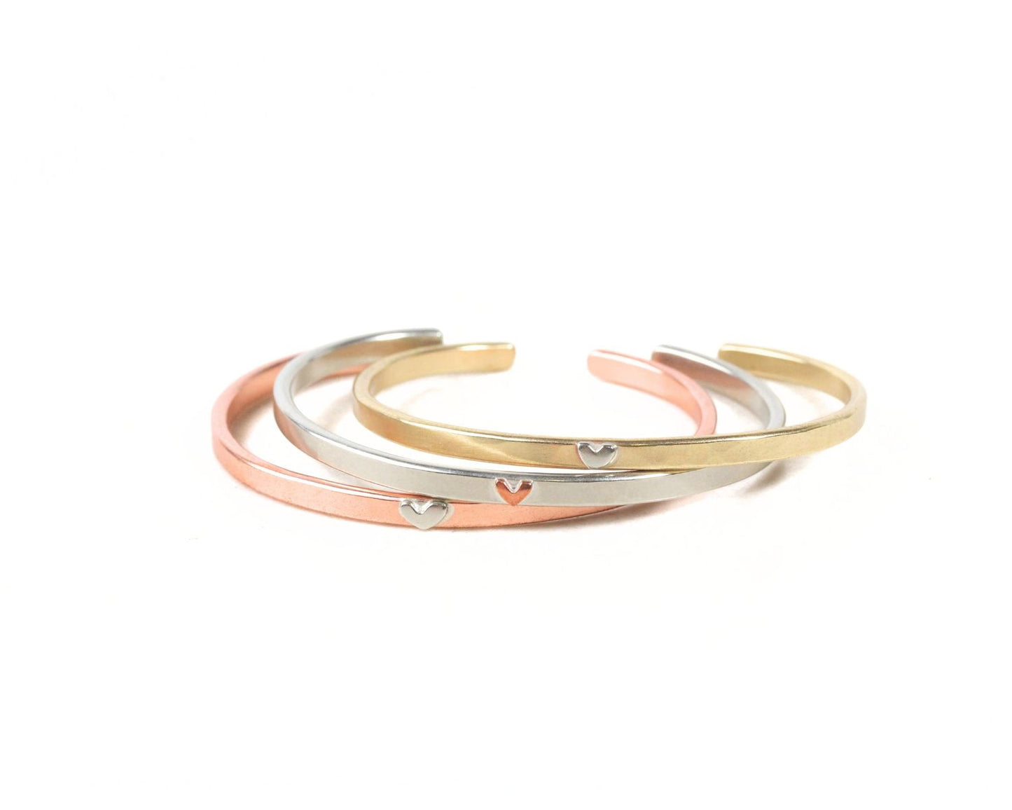 A group of three bracelets with heart-shaped charms on them, arranged in a circular pattern.