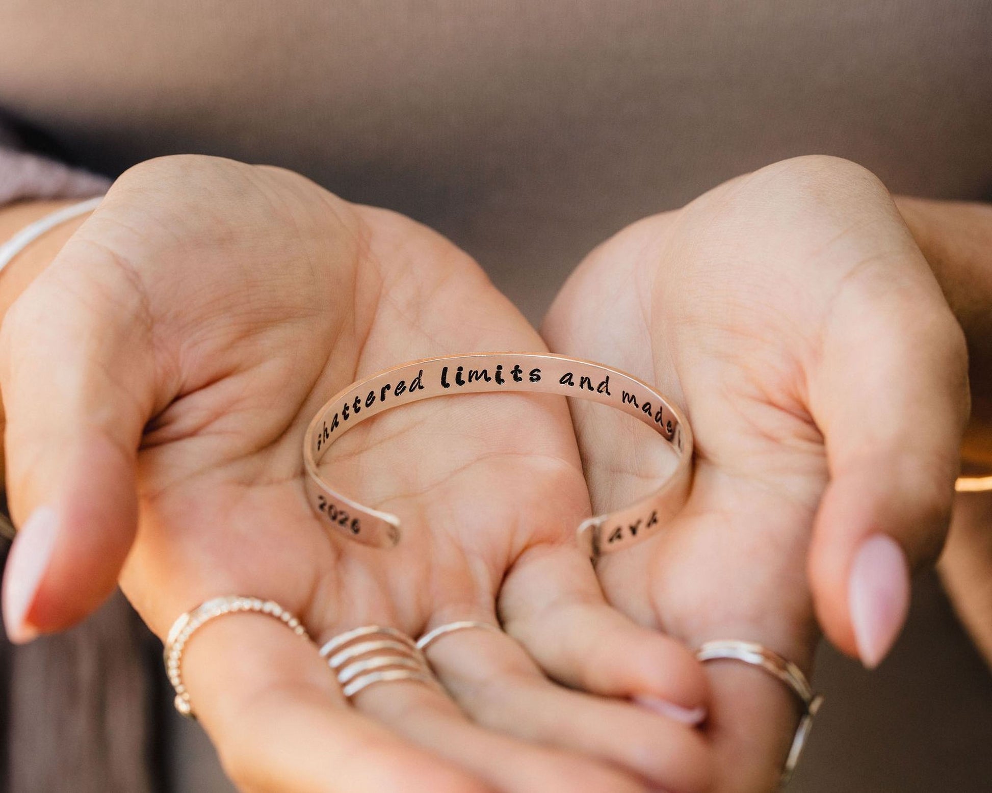 A person's hand holding a bracelet with the text "Bracelet" and "Limits and boundaries" engraved on it.