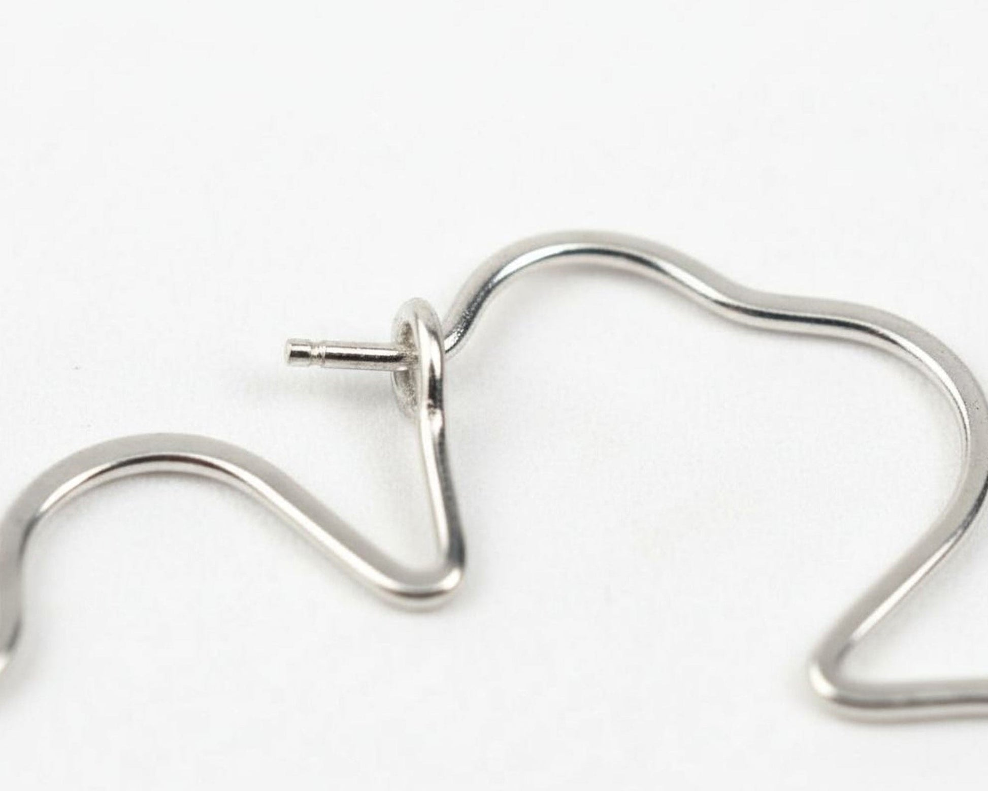 A close-up view of a silver-colored metal wire or chain with a twisted shape, possibly resembling a bracelet or necklace.