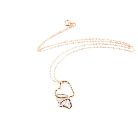 A delicate gold necklace with a heart-shaped pendant featuring two intertwined hearts.