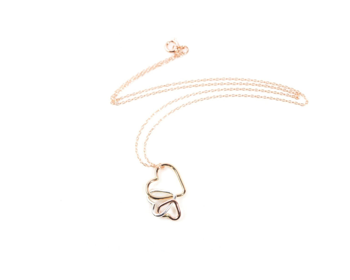 A delicate gold necklace with a heart-shaped pendant featuring two intertwined hearts.