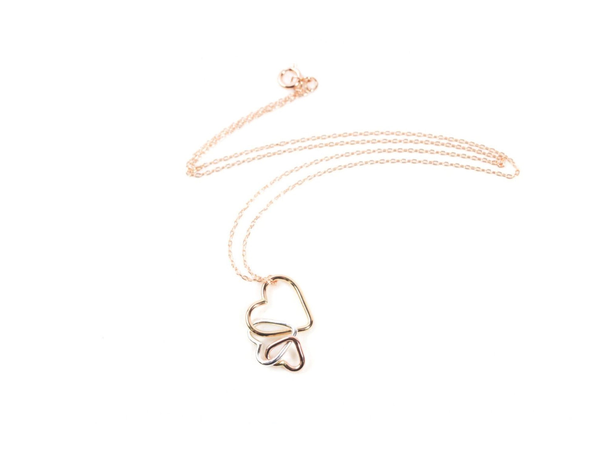 A delicate gold necklace with a heart-shaped pendant featuring two intertwined hearts.