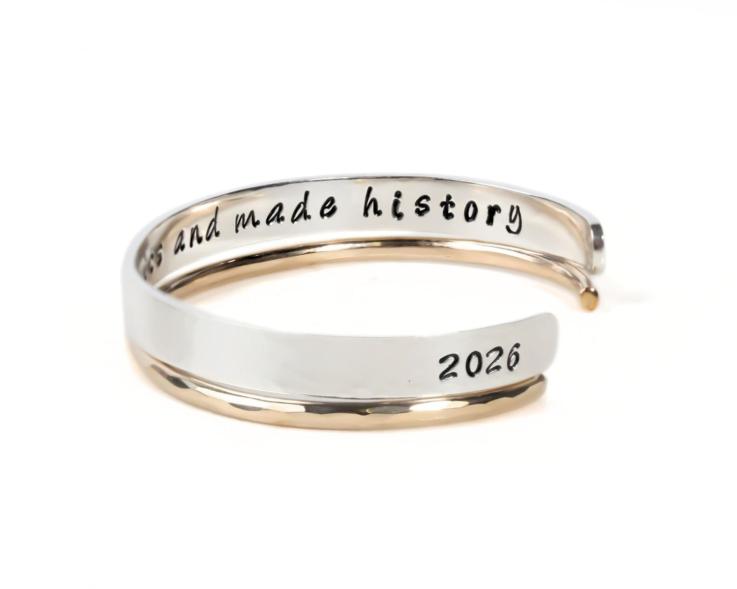 A silver and gold bracelet with the text "History and made history" engraved on it.