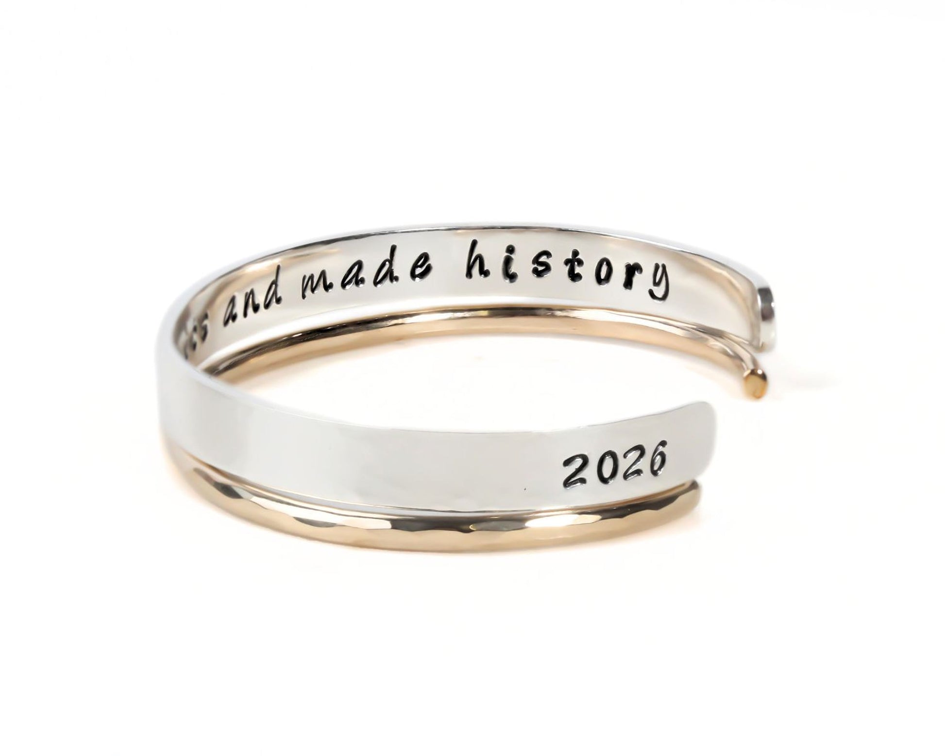 A silver and gold bracelet with the text "History and made history" engraved on it.