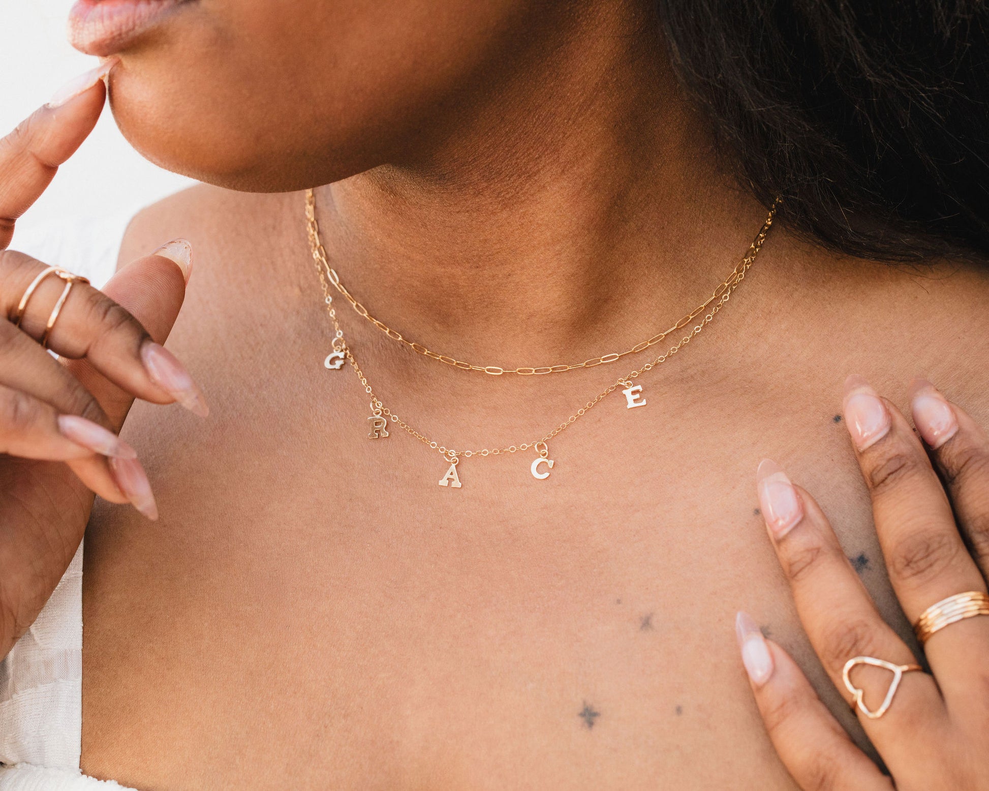 A close-up of a person's neck and chest area, featuring a necklace with the name 'Grace' engraved on it.