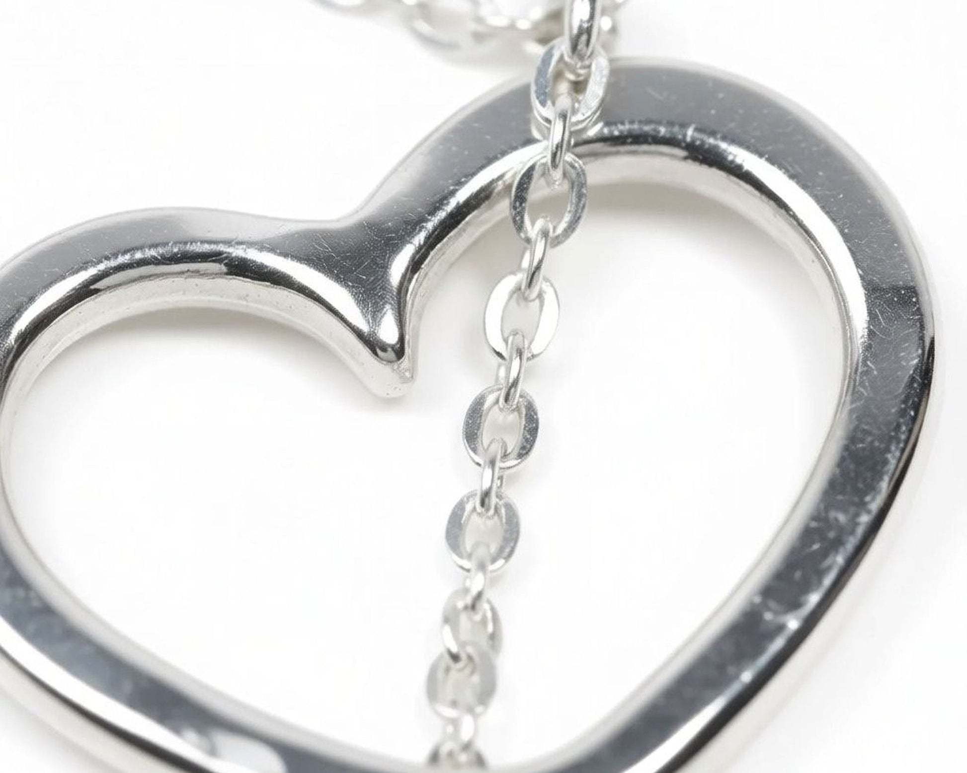 A close-up image of a silver heart-shaped pendant with a chain attached to it.