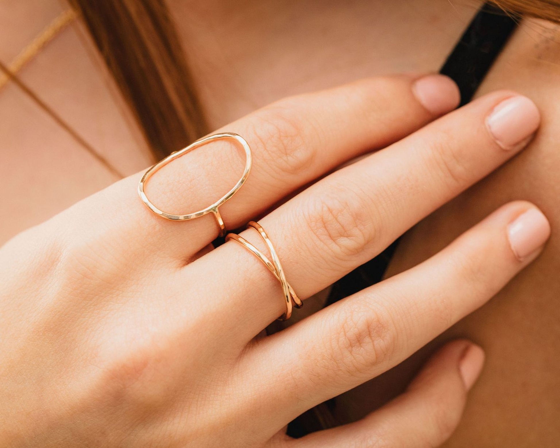 A close-up of a person's hand wearing two gold rings on the fingers.