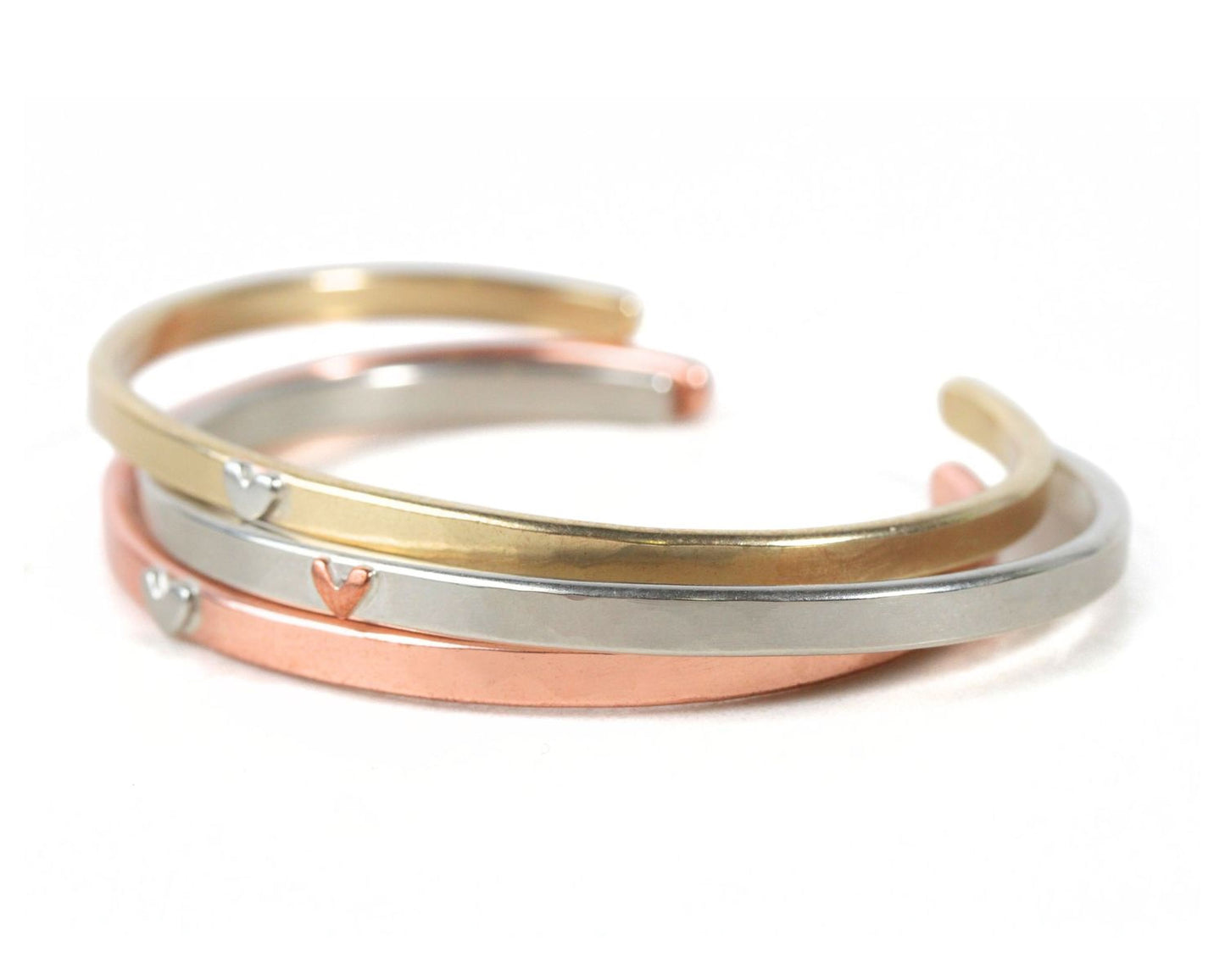A stack of three colorful bracelets with heart-shaped charms on them.