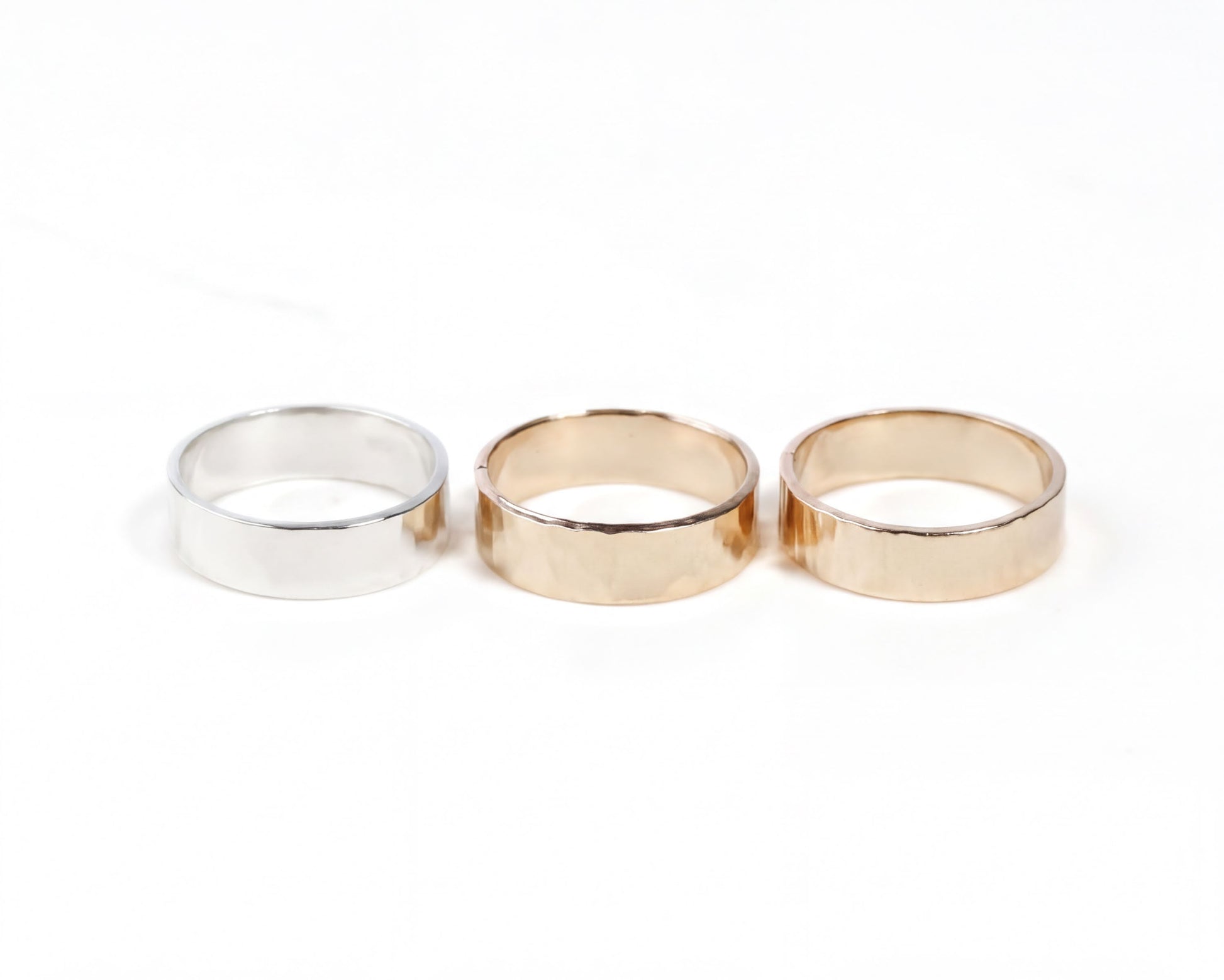 Three rings of different colors - silver, gold, and gold - are displayed against a white background.