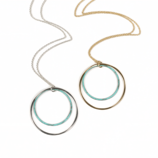 two circular necklaces with different color rings, one silver and one gold, hanging from a chain.