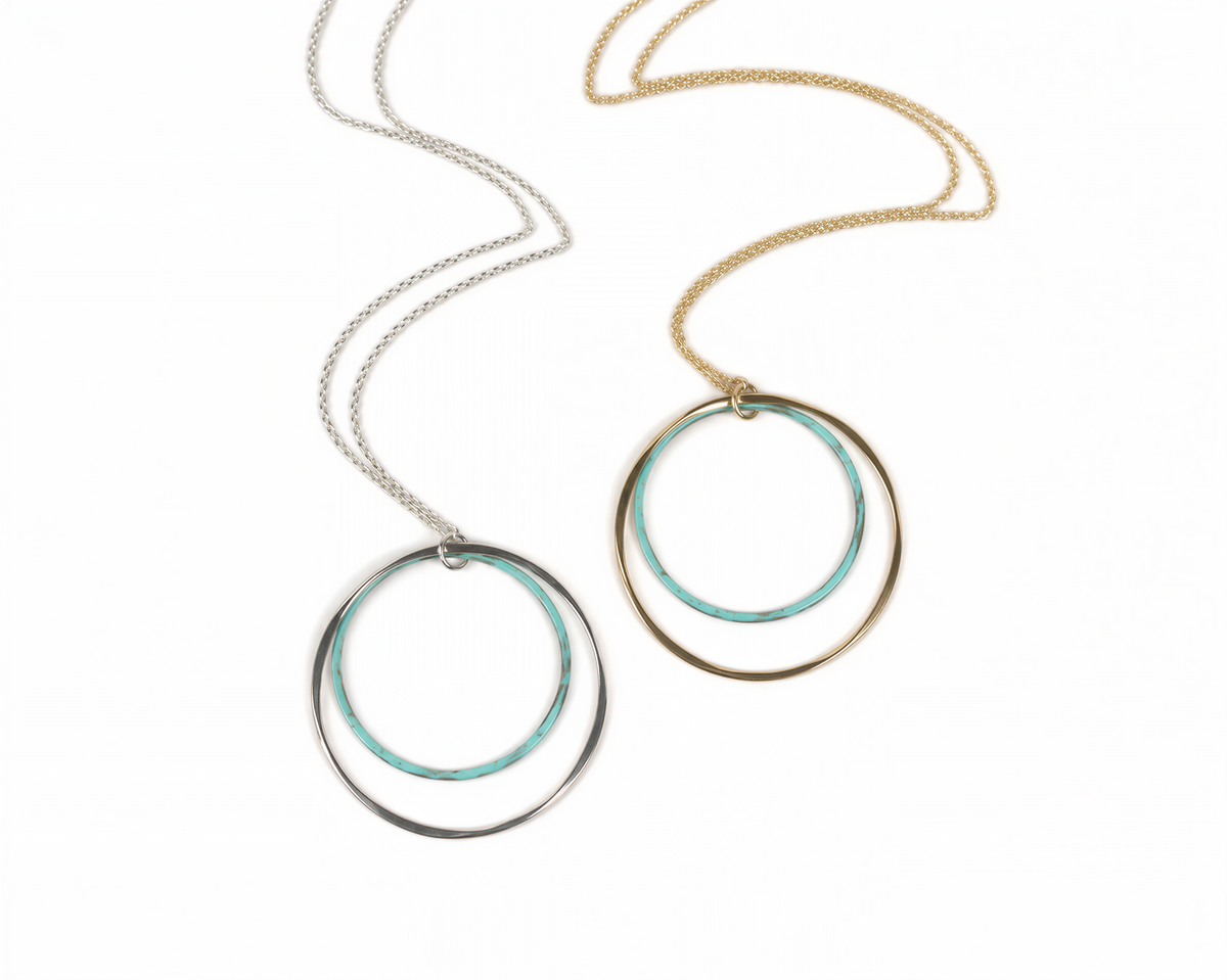 two circular necklaces with different color rings, one silver and one gold, hanging from a chain.