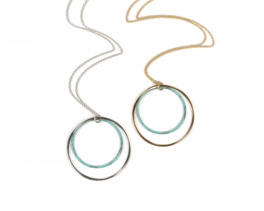 two circular necklaces with different color rings, one silver and one gold, hanging from a chain.
