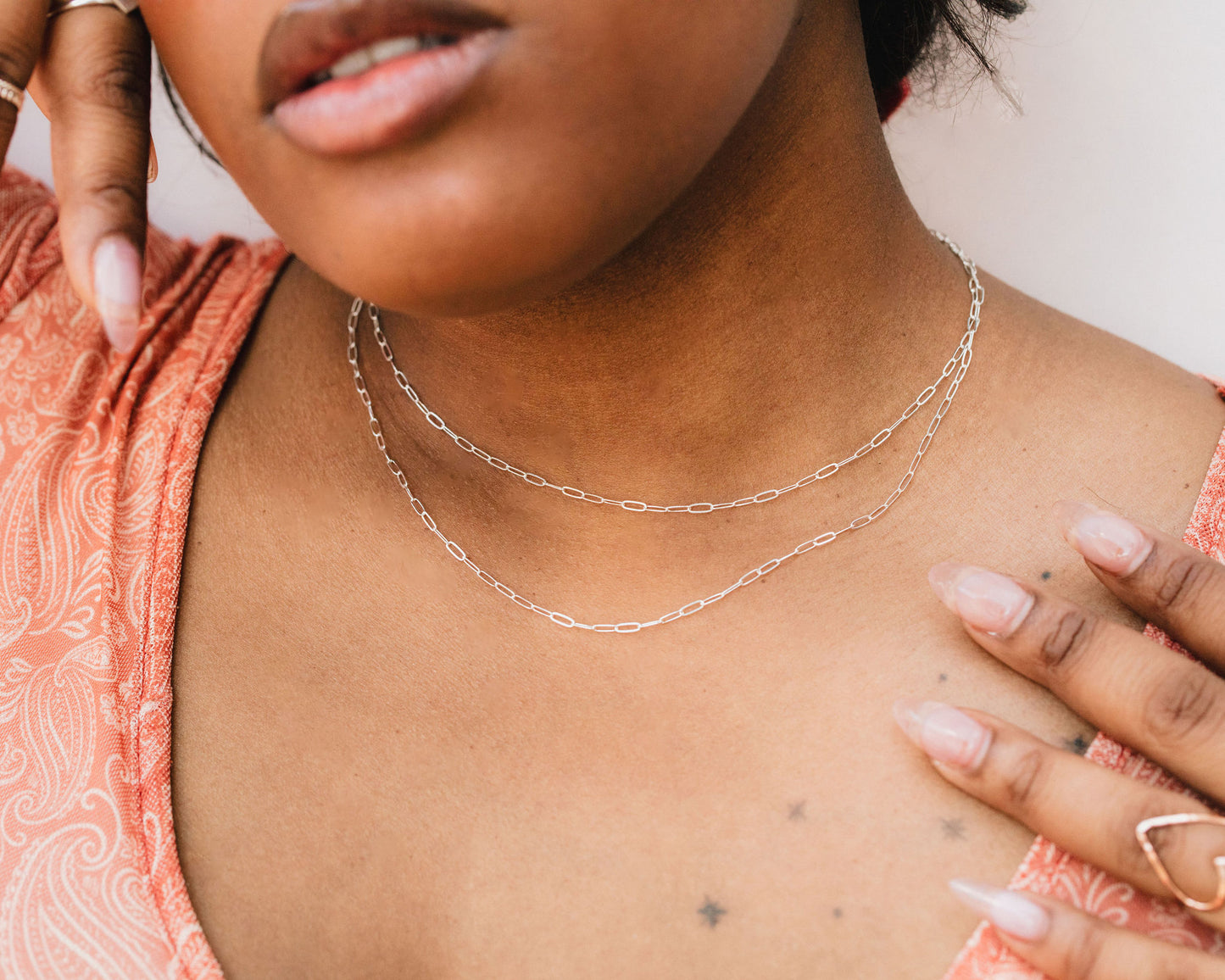A close-up of a woman's neck and chest area, with a necklace visible.