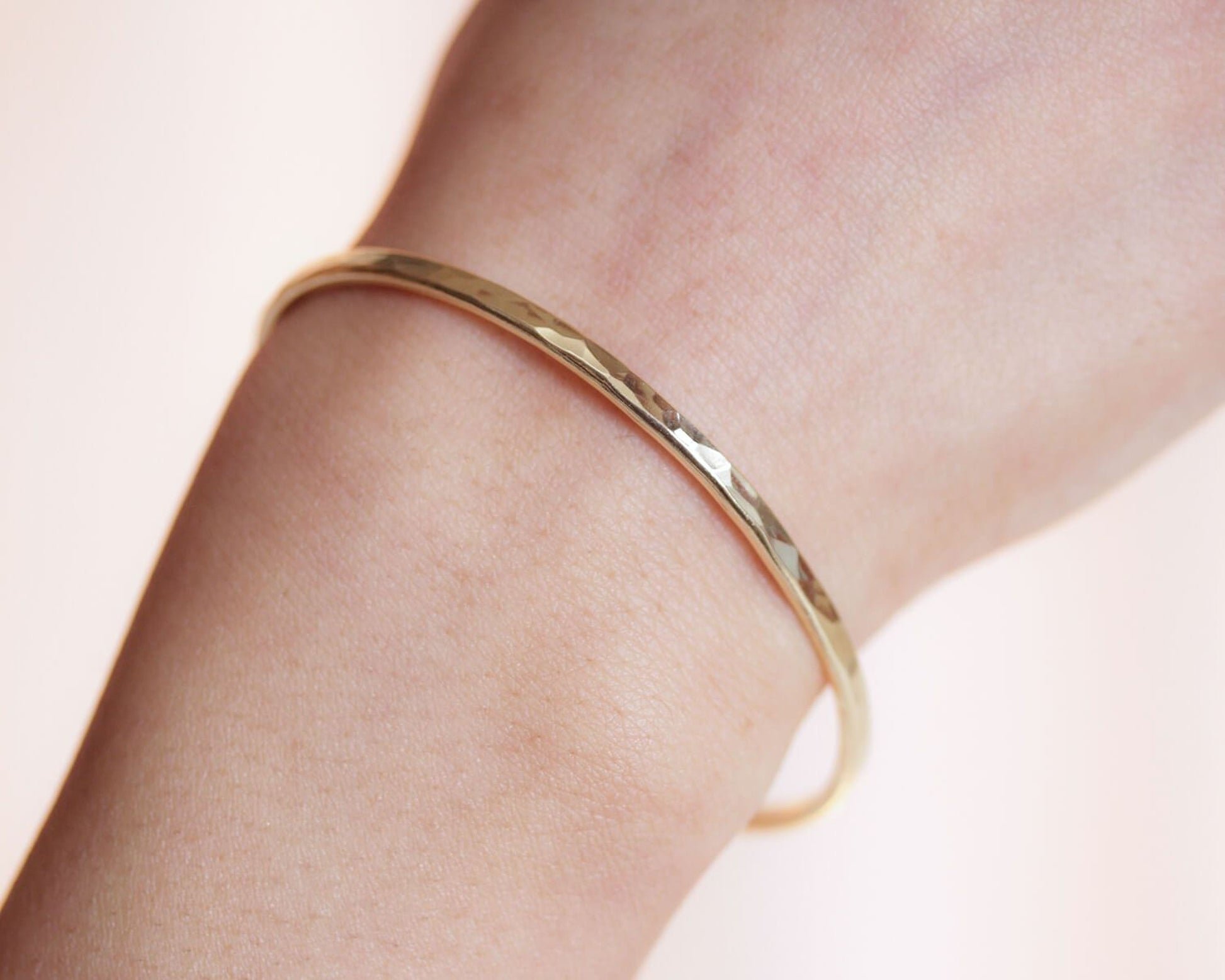A gold-colored bangle bracelet is worn on a person's wrist.