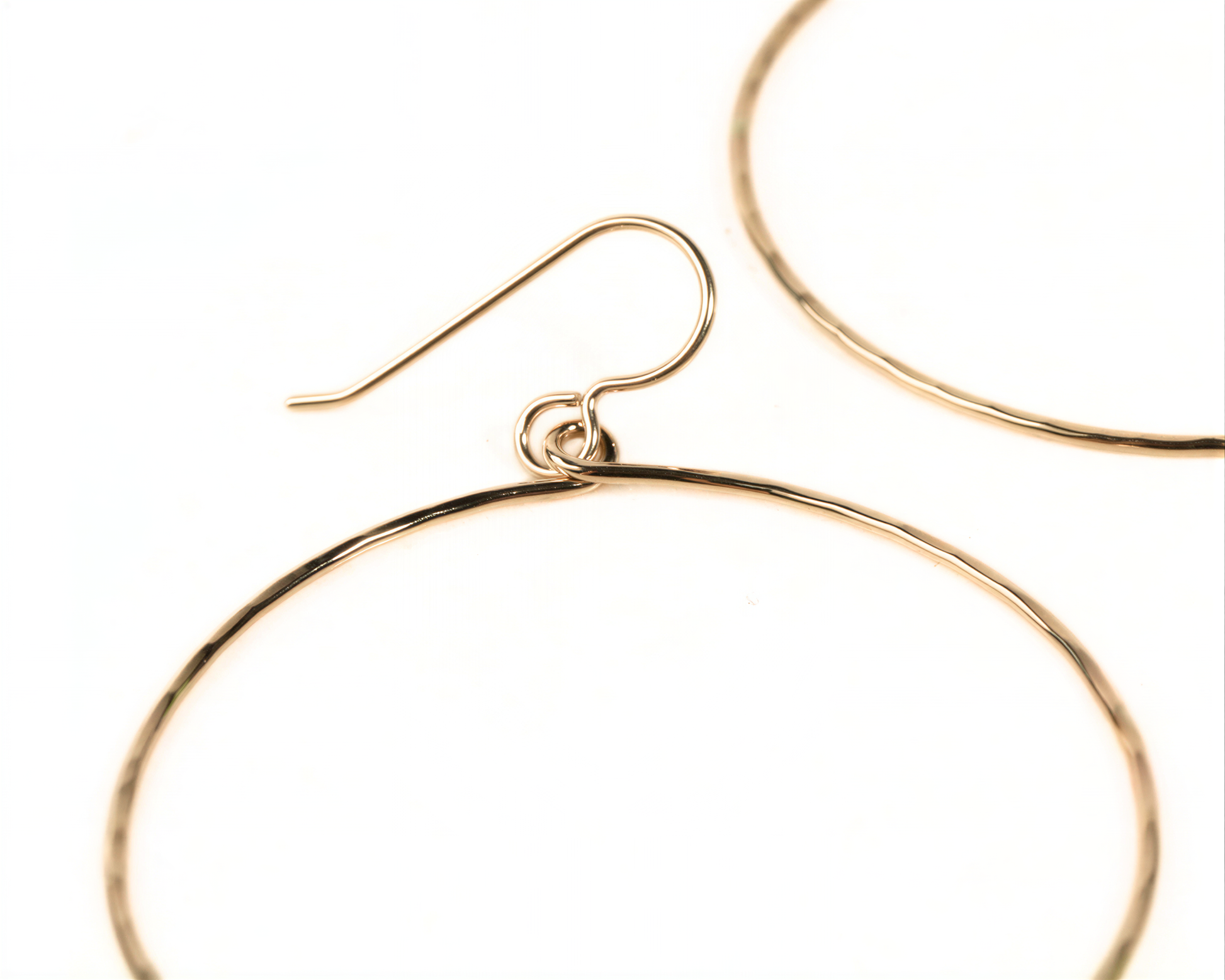 A pair of gold hoop earrings with a hook and a small loop.