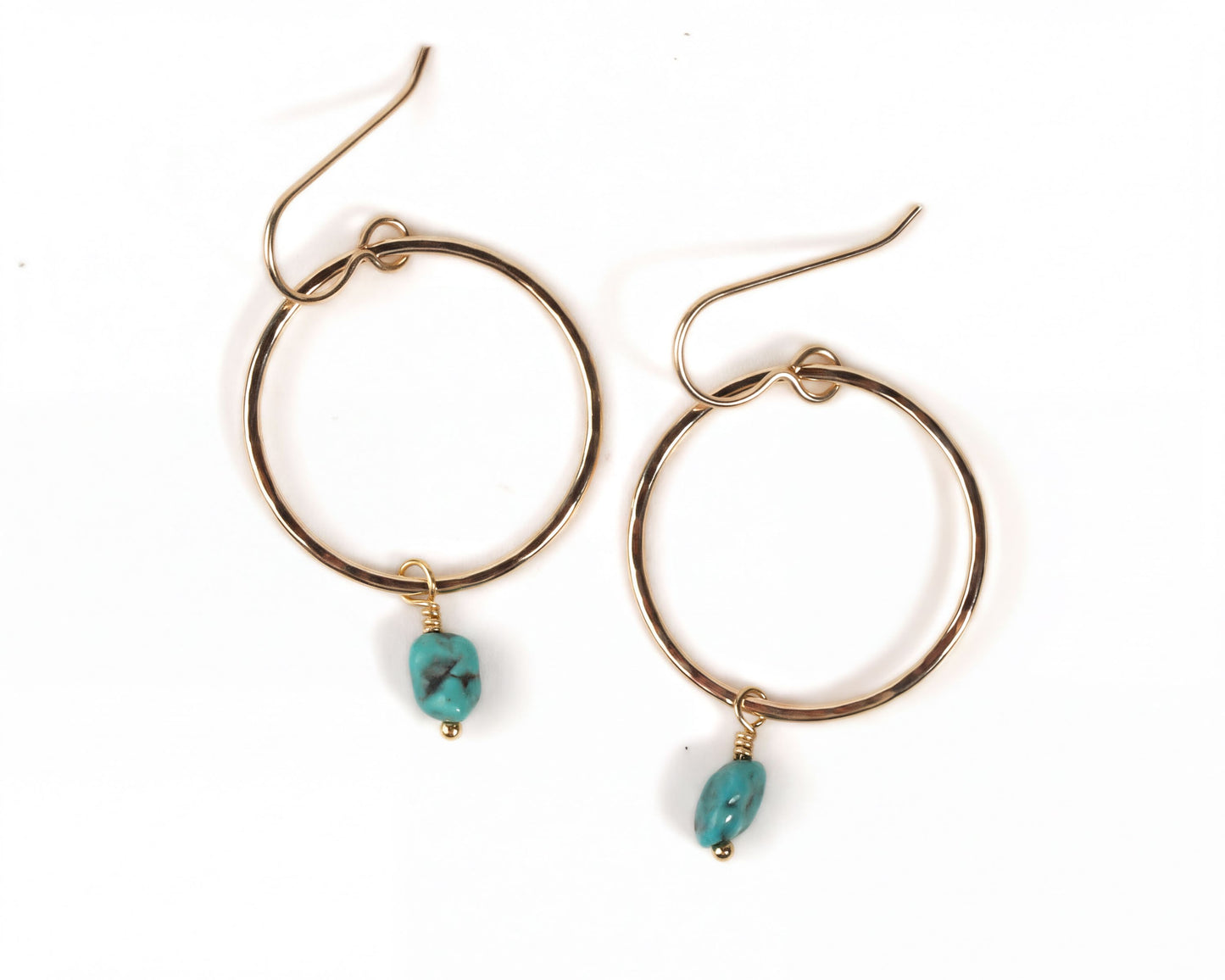 A pair of gold hoop earrings with turquoise stones hanging from the hooks.