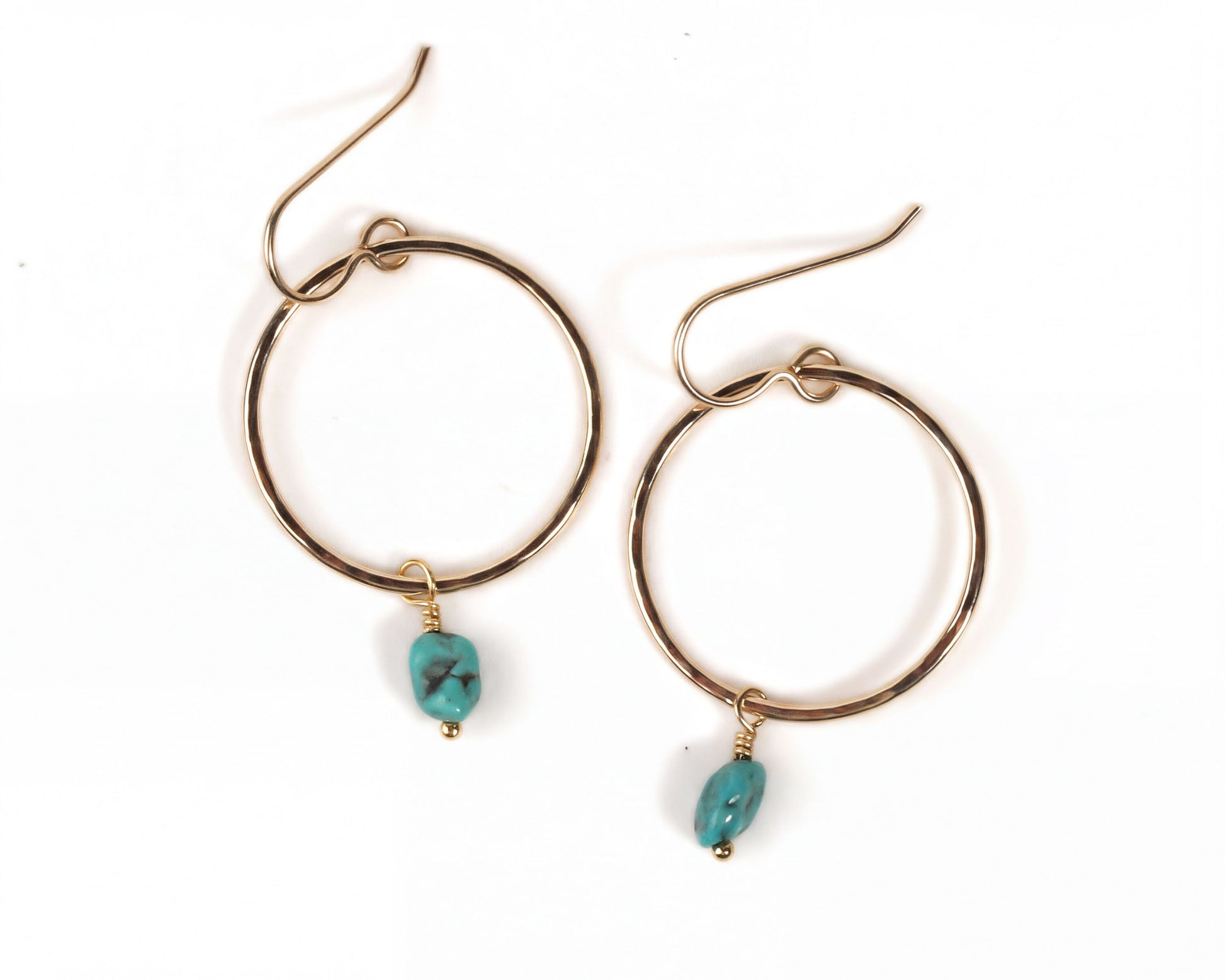 A pair of gold hoop earrings with turquoise stones hanging from the hooks.